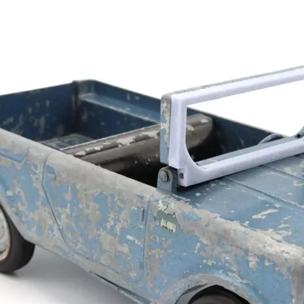 A worn blue toy truck with a saw mounted on its bed.