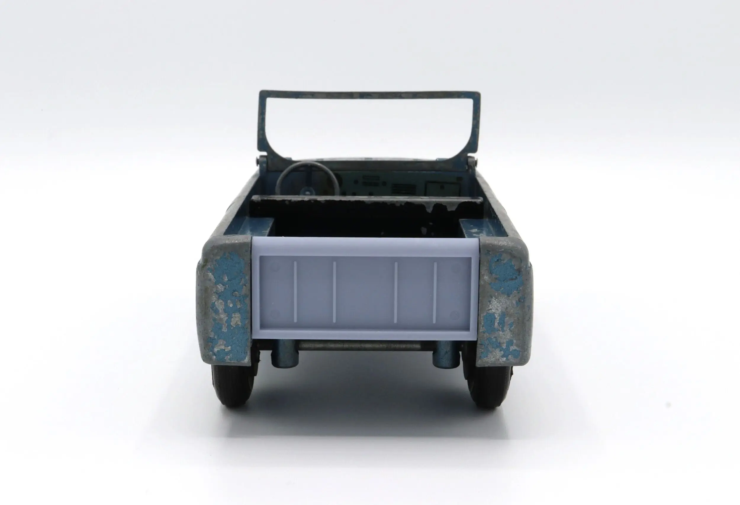 Rear view of a toy pickup truck with an open bed and handle.