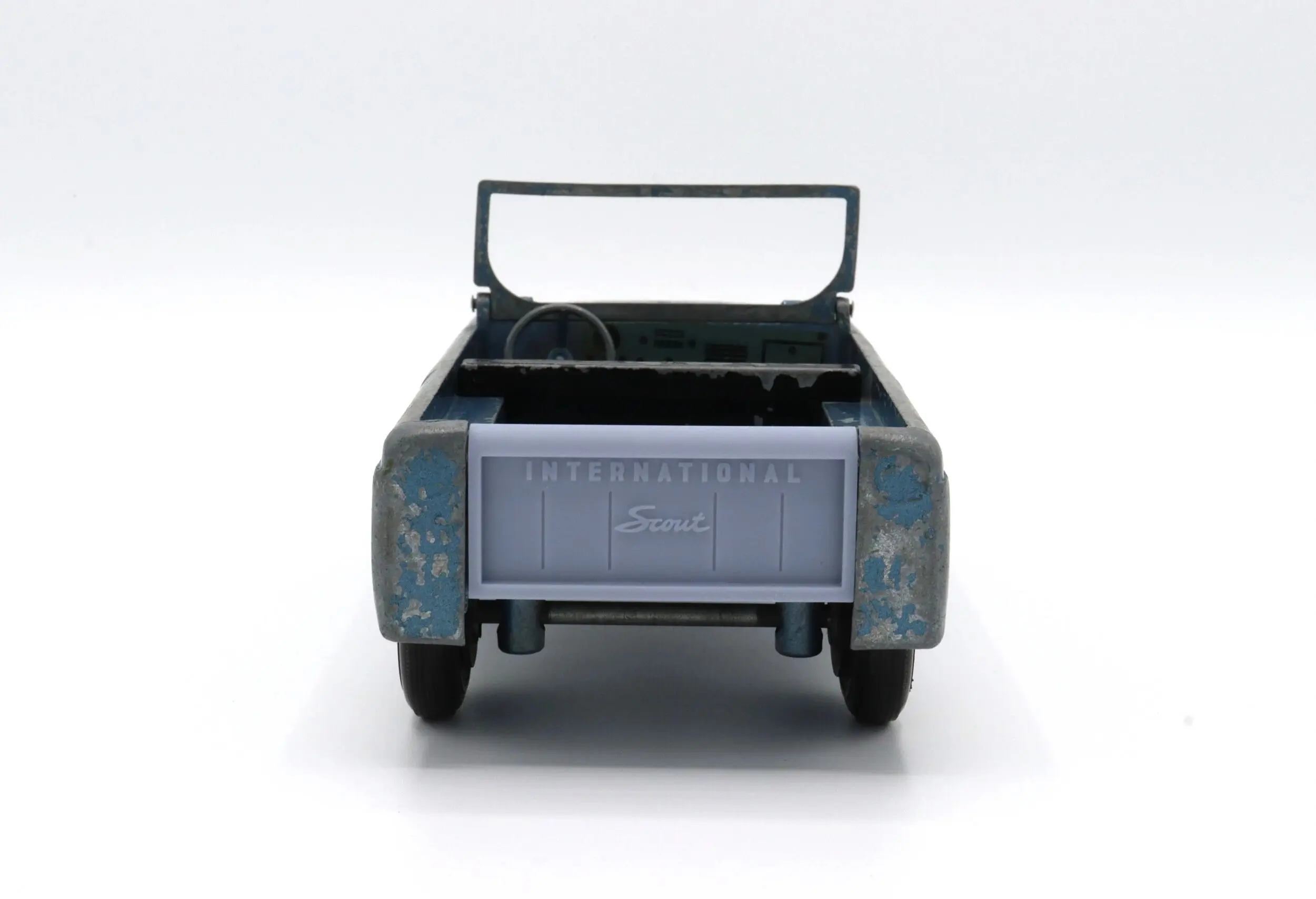 Rear view of a small blue toy pickup truck with an open bed.