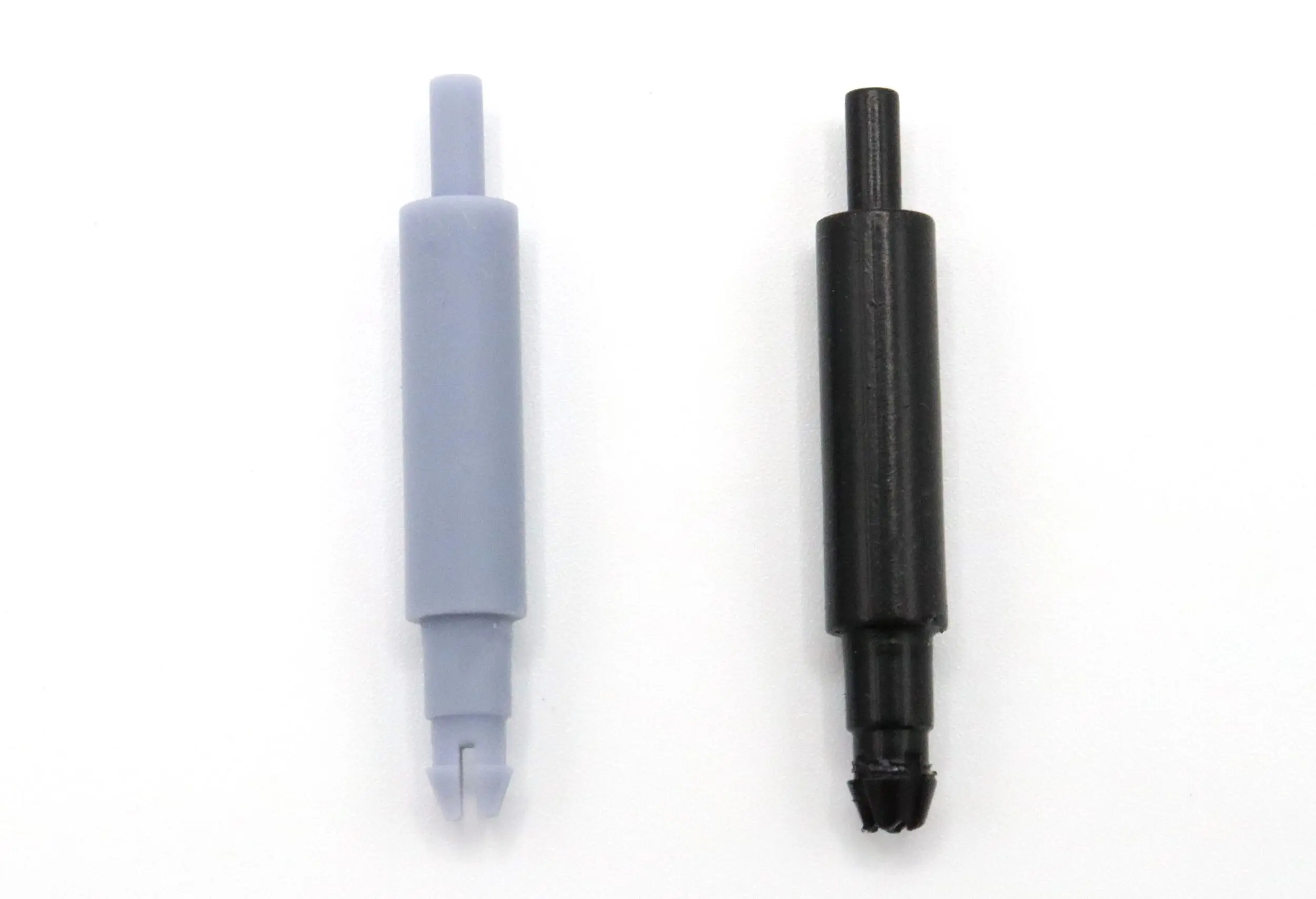 Two plastic syringe-like components, one gray and one black, with ridged ends.