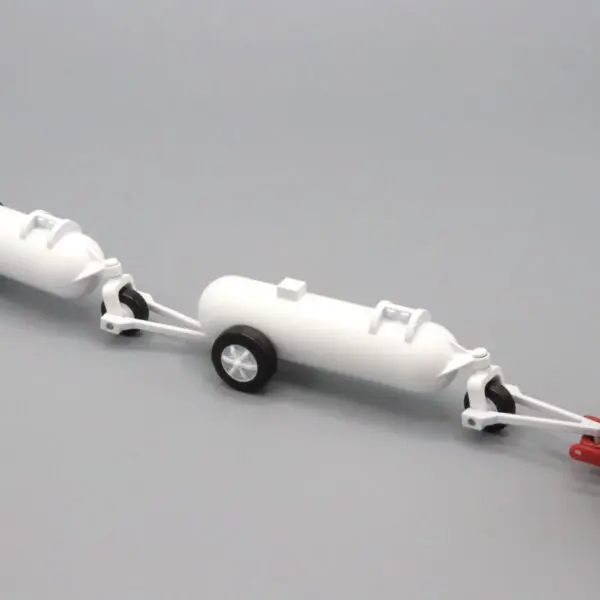 Two small white model trailers with wheels connected in a line on a gray surface.