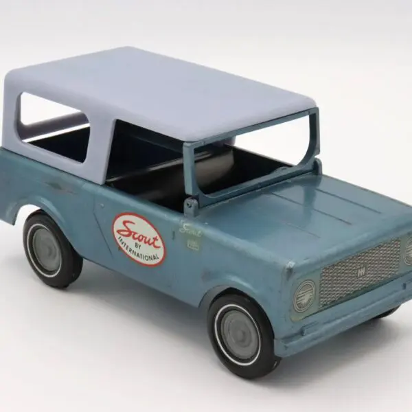 A vintage blue toy car with a white roof and logo on the door.