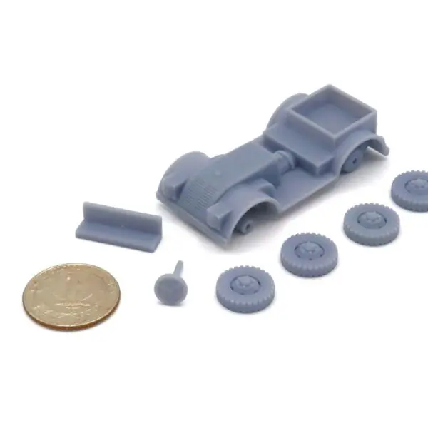 Unassembled small-scale model car parts with a coin for size reference.