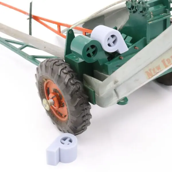 Close-up of a tractor wheel with two gray plastic caps beside it.