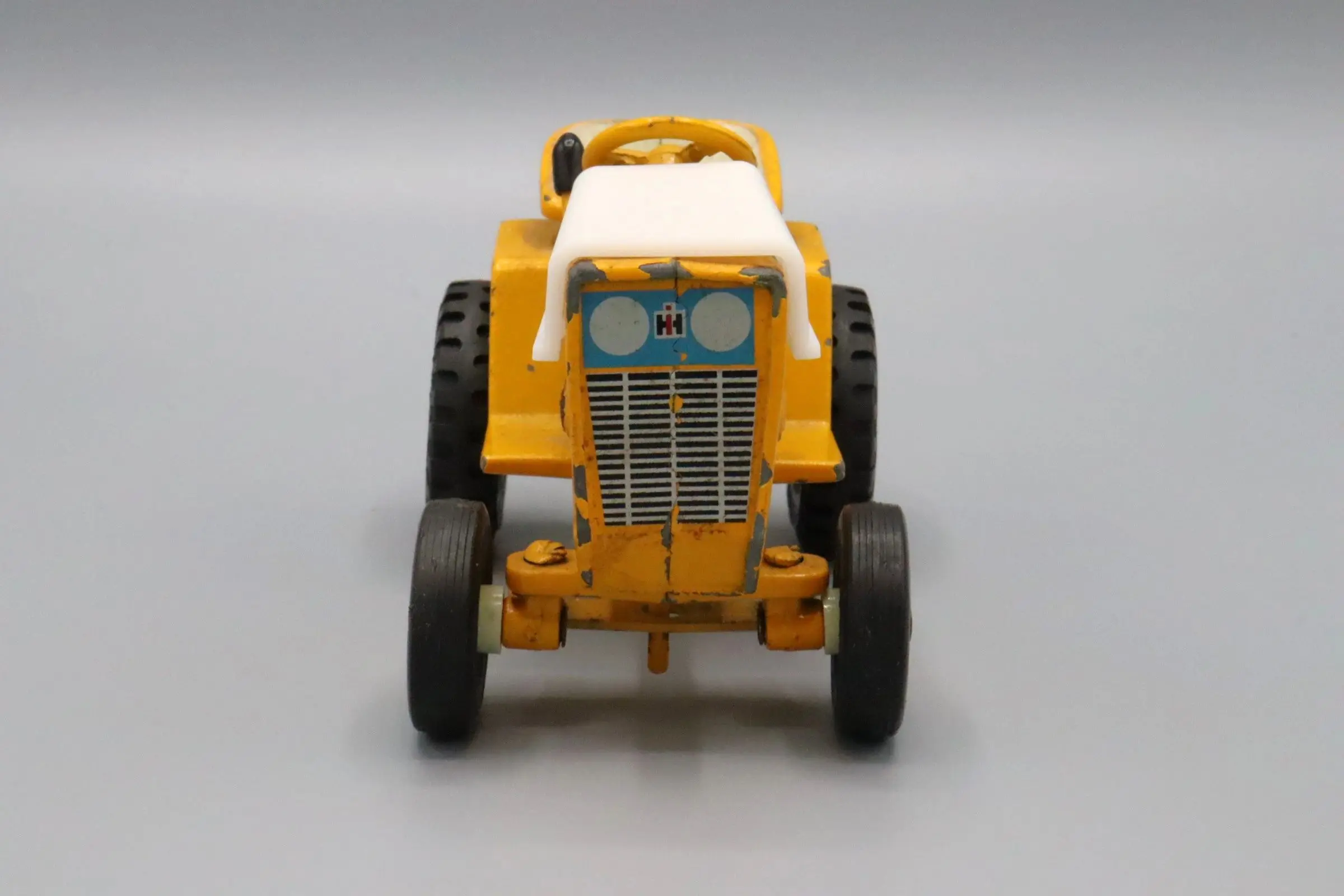 Front view of a yellow toy tractor with black tires.