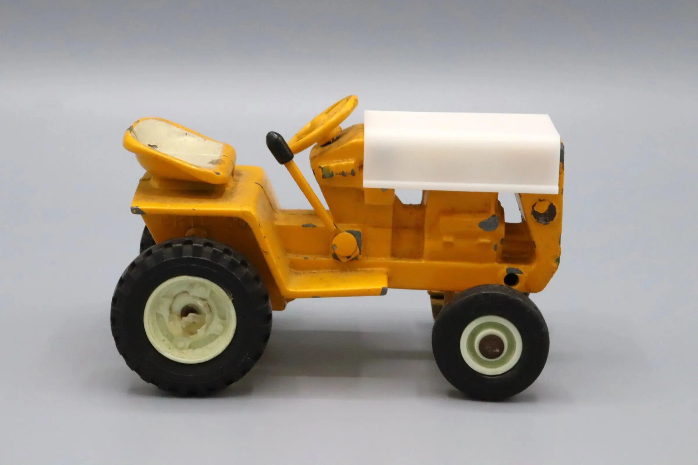 A small yellow toy tractor with a white canopy.
