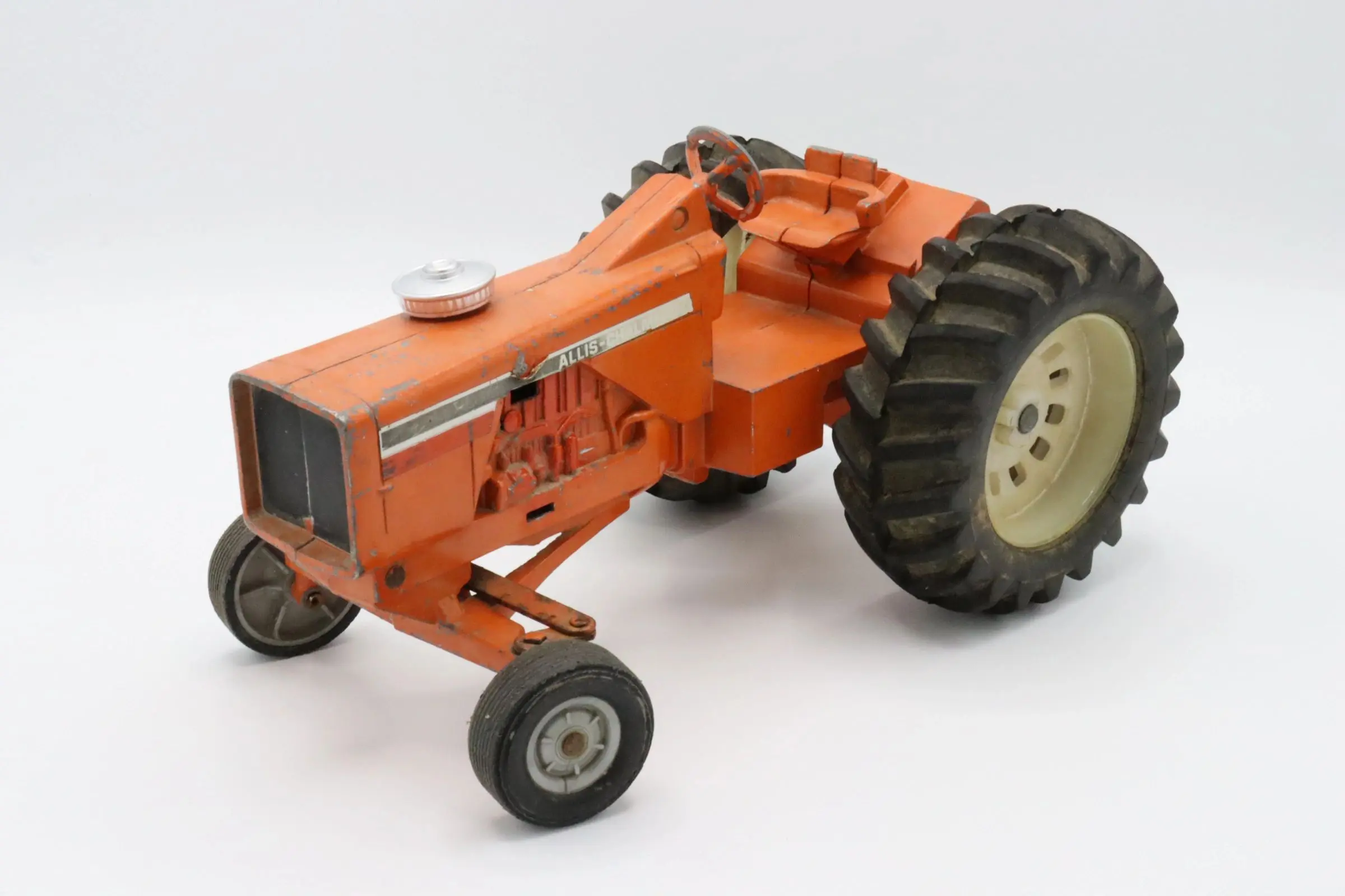 A vintage orange toy tractor with large rear wheels.