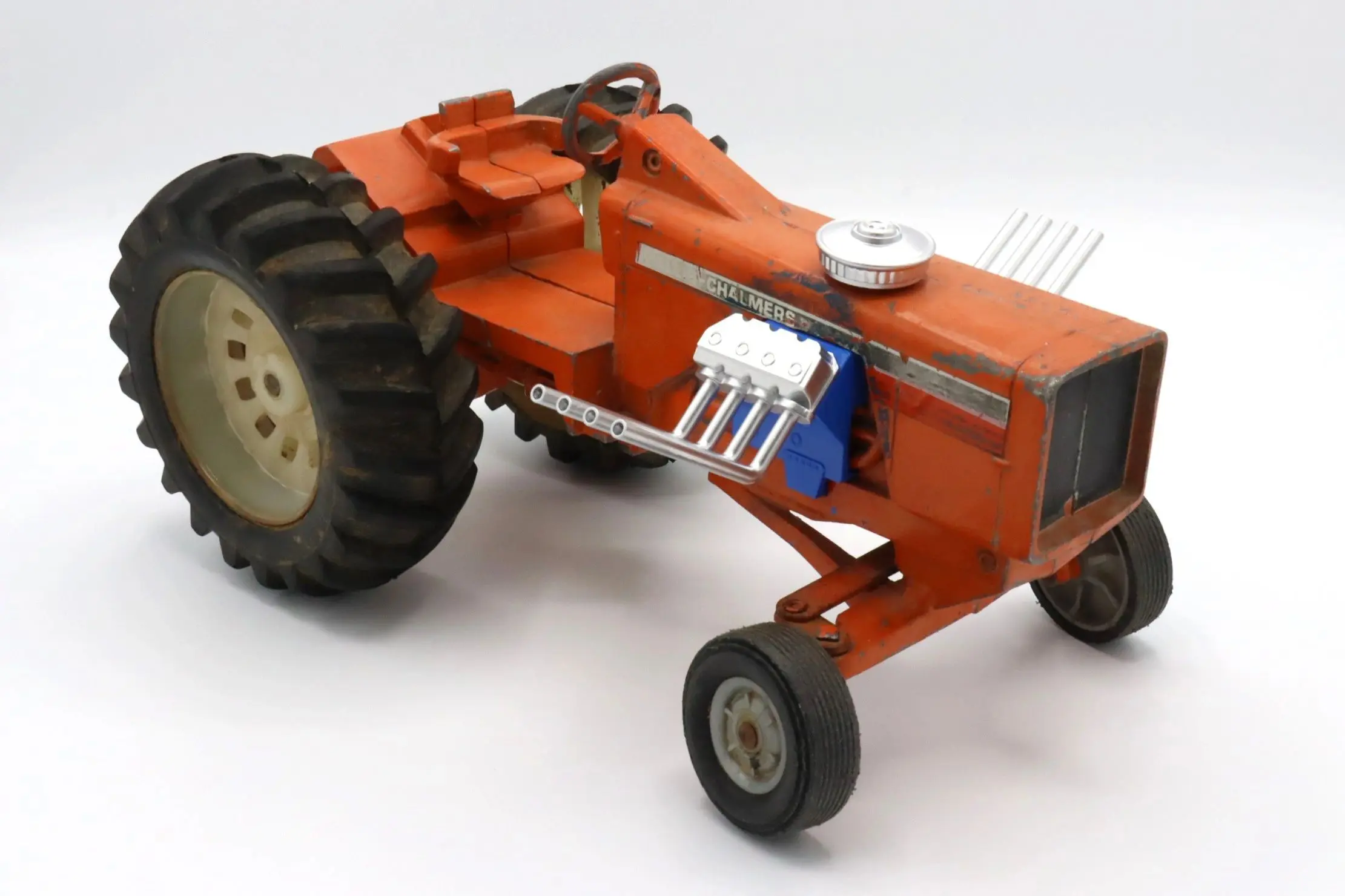A detailed miniature model of an orange tractor with visible engine parts.
