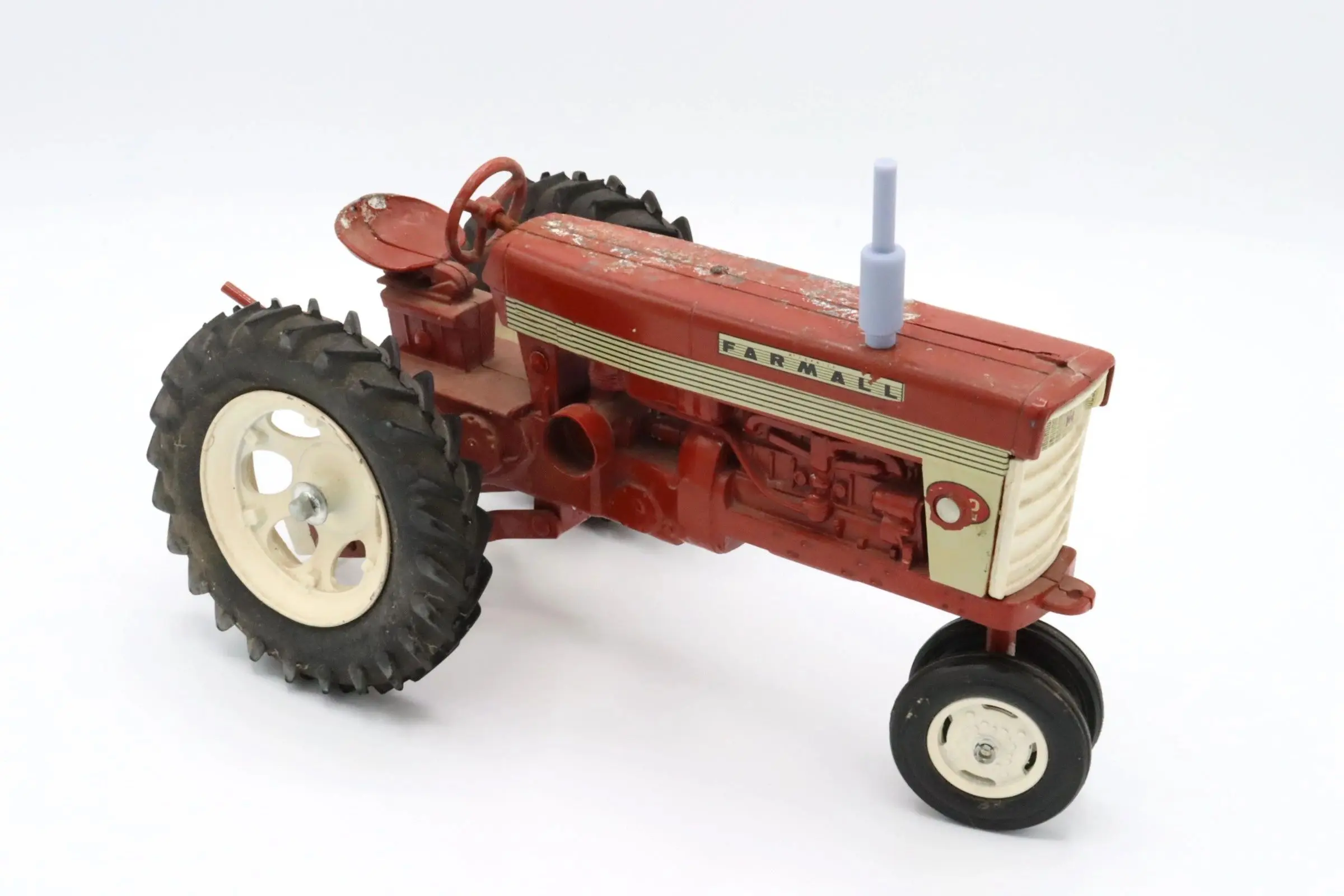 A vintage red Farmall tractor model with large rear tires.