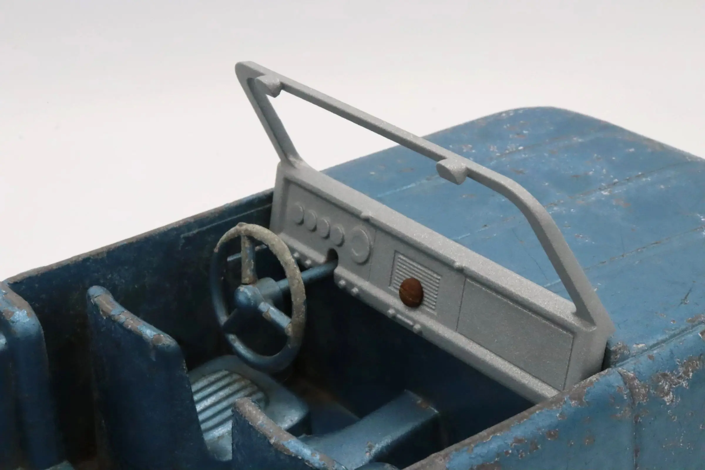 Interior of a vintage blue vehicle with a simple dashboard and steering wheel.