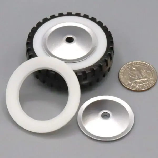 Disassembled metal wheel with rubber tire and coin for scale.