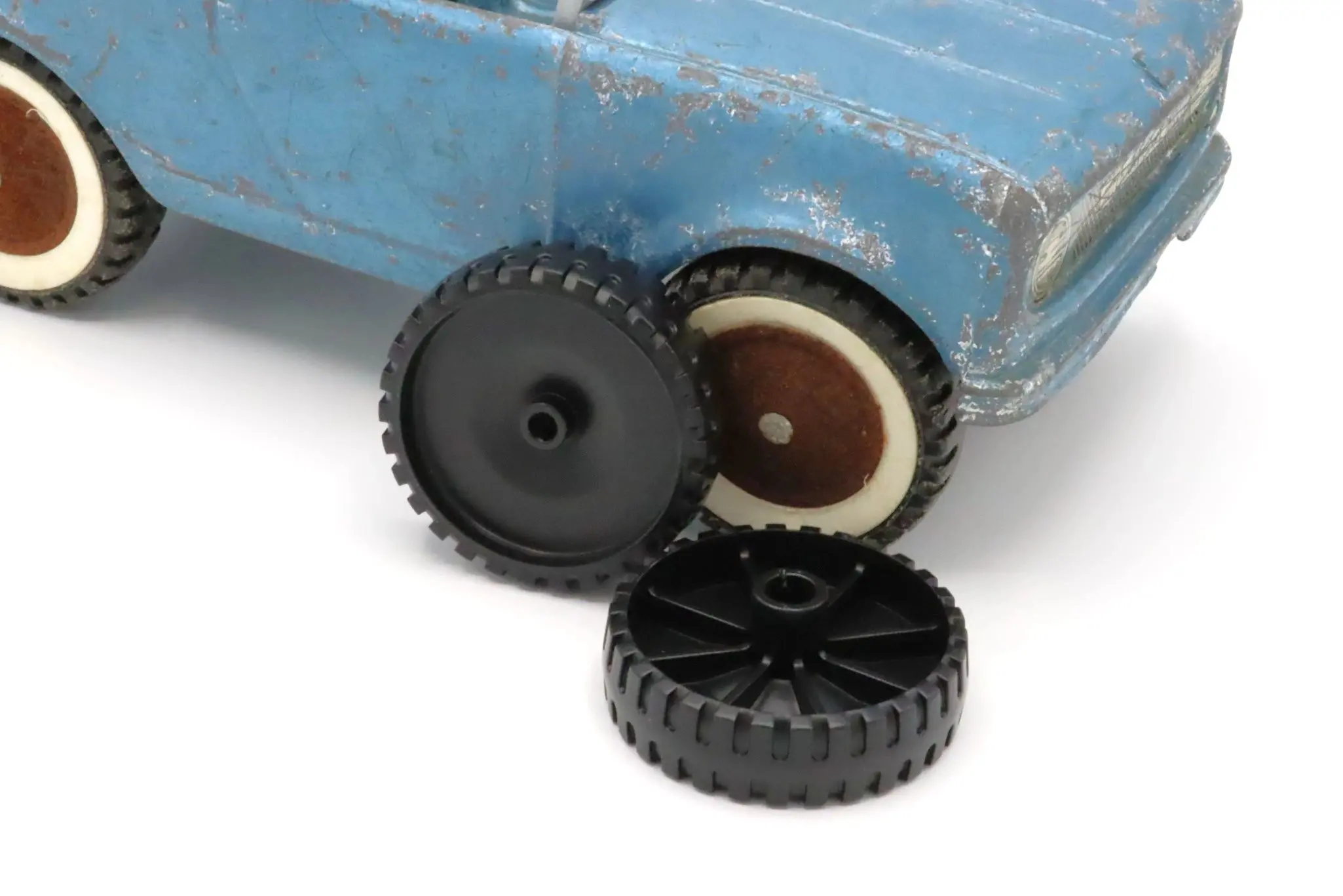 Close-up of a toy car's broken wheel and replacement parts.