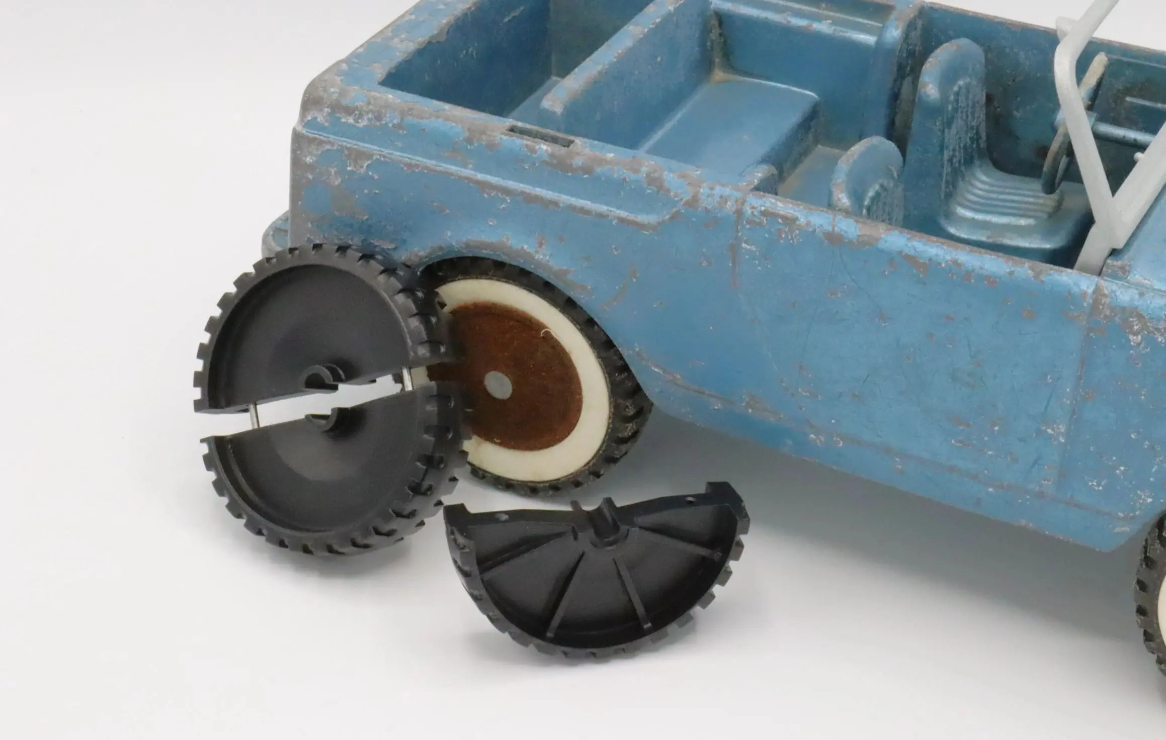 Broken black plastic wheel beside a blue toy car.