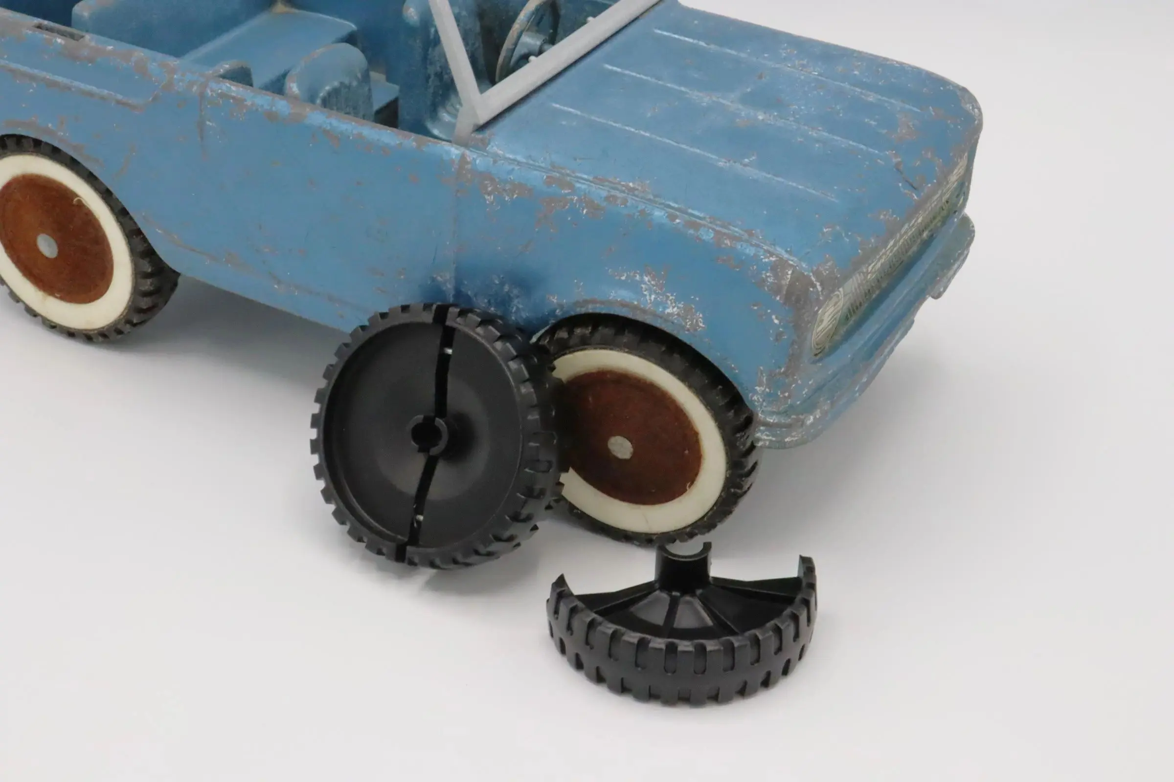 A toy car with broken plastic wheels beside it.