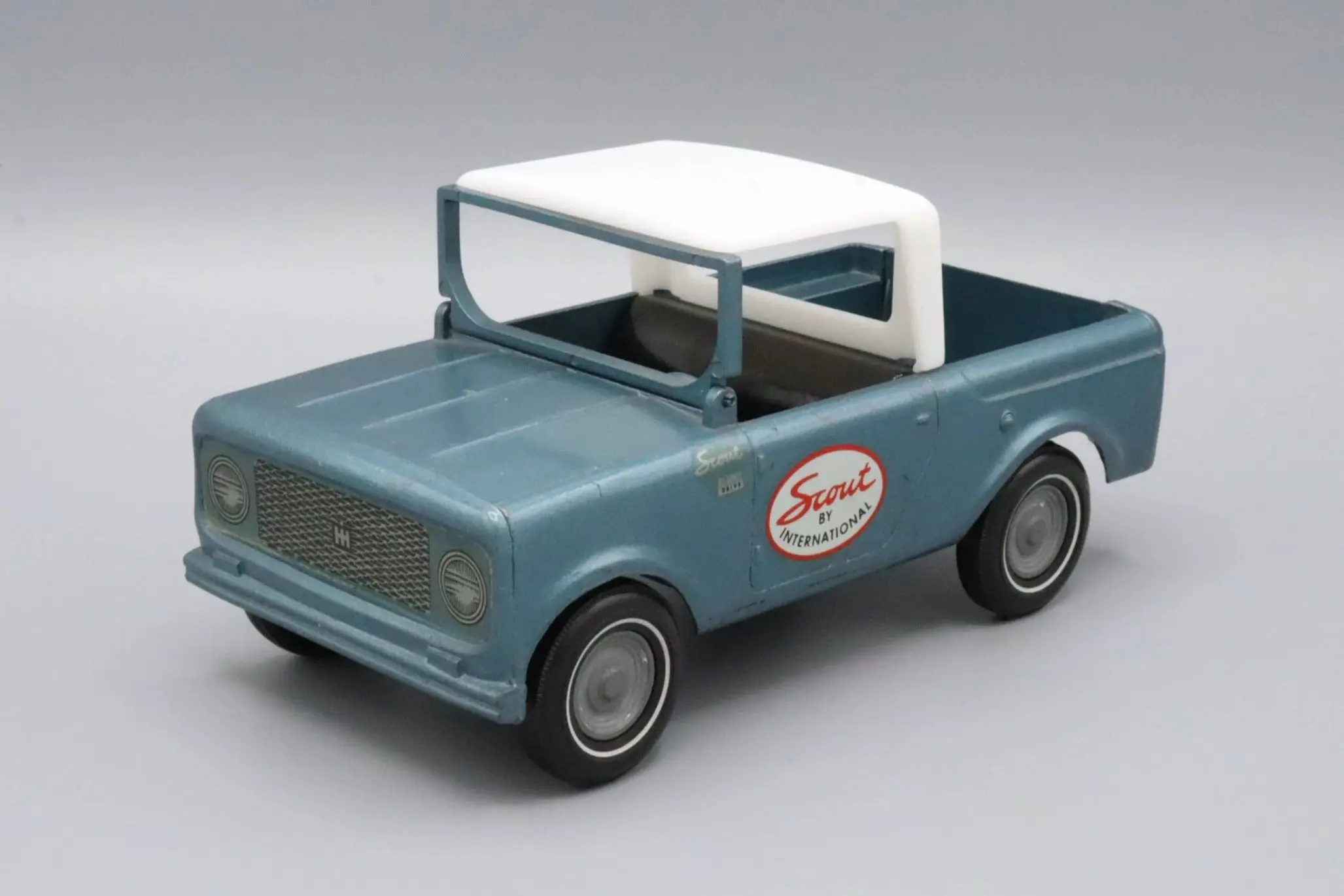 Vintage blue and white toy pickup truck with logo on door.