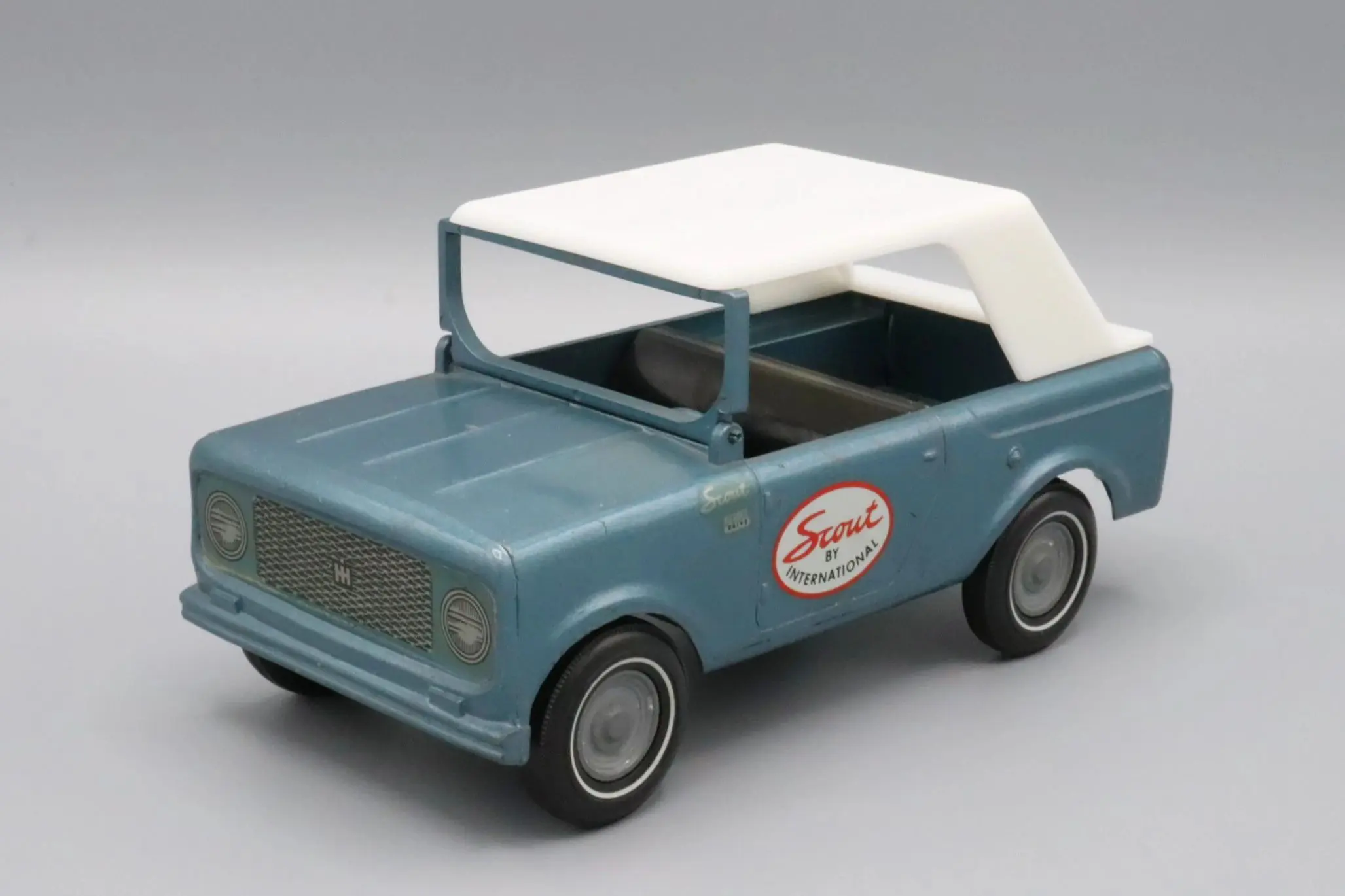 Vintage blue toy car with a white roof and logo on the door.
