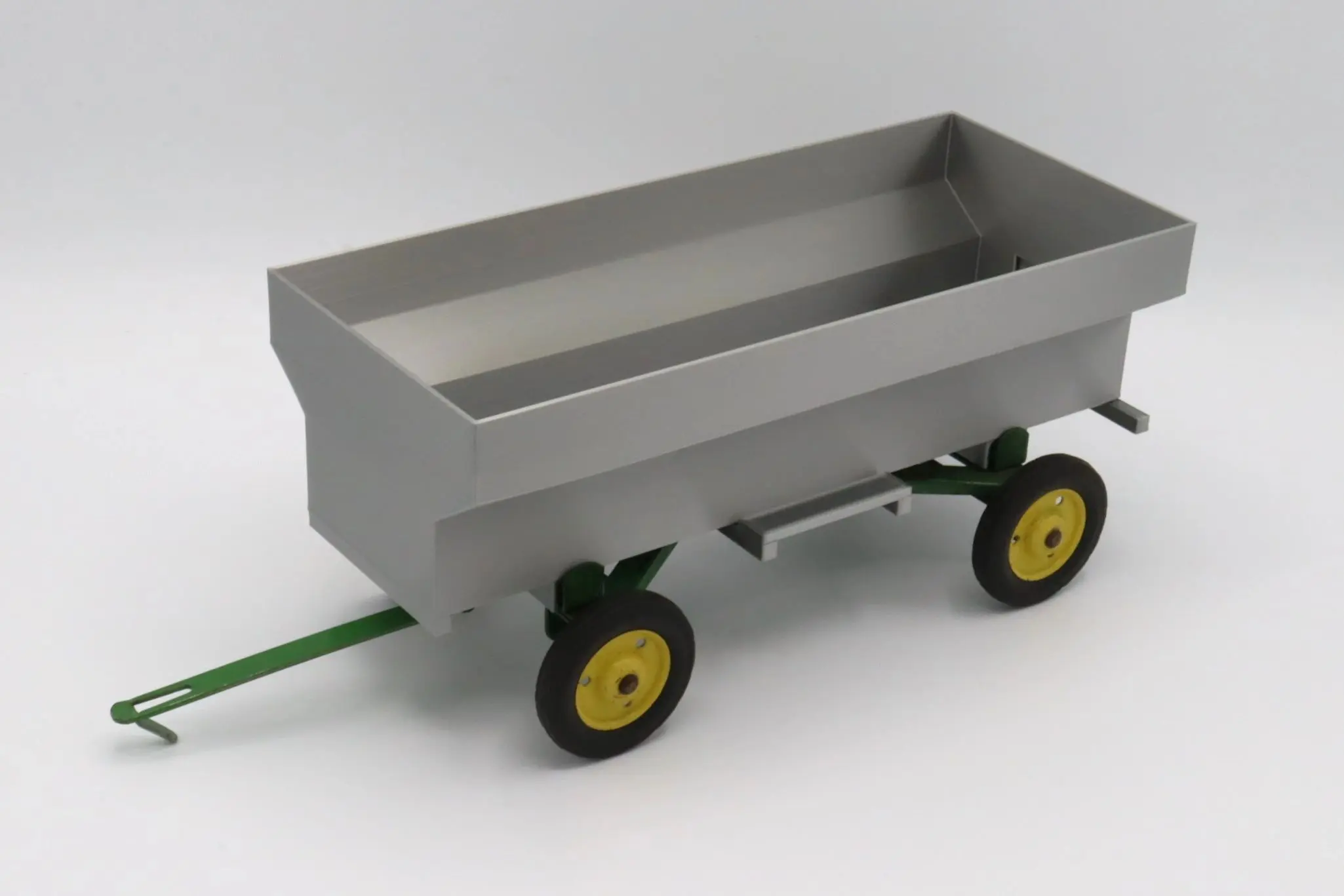 A small gray toy wagon with yellow and black wheels.