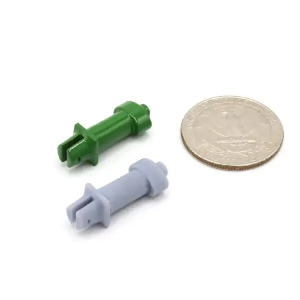 Two small plastic connectors next to a coin for size reference.