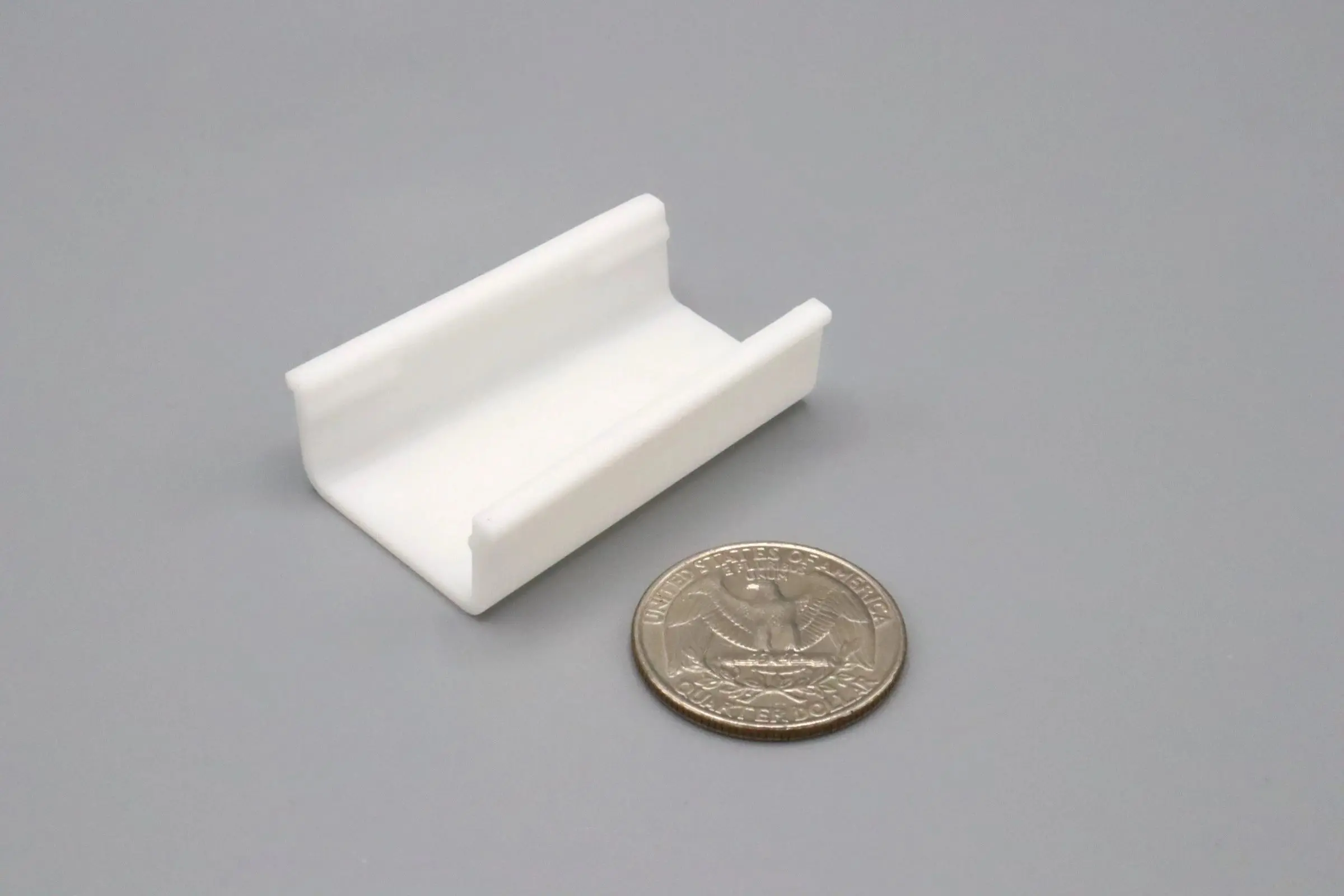 Small white plastic clip next to a quarter for scale.