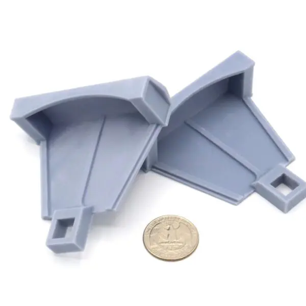 Two gray plastic corner brackets placed beside a coin for scale.