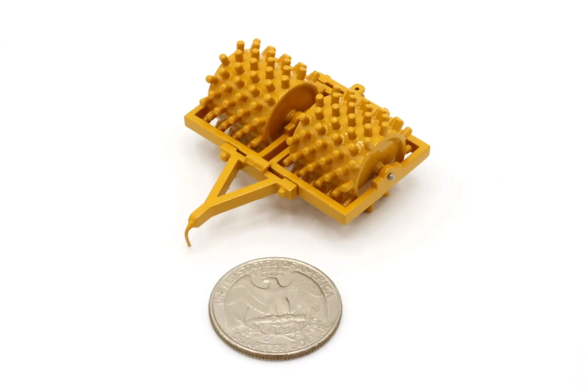 A small, yellow waffle maker toy next to a coin for scale.