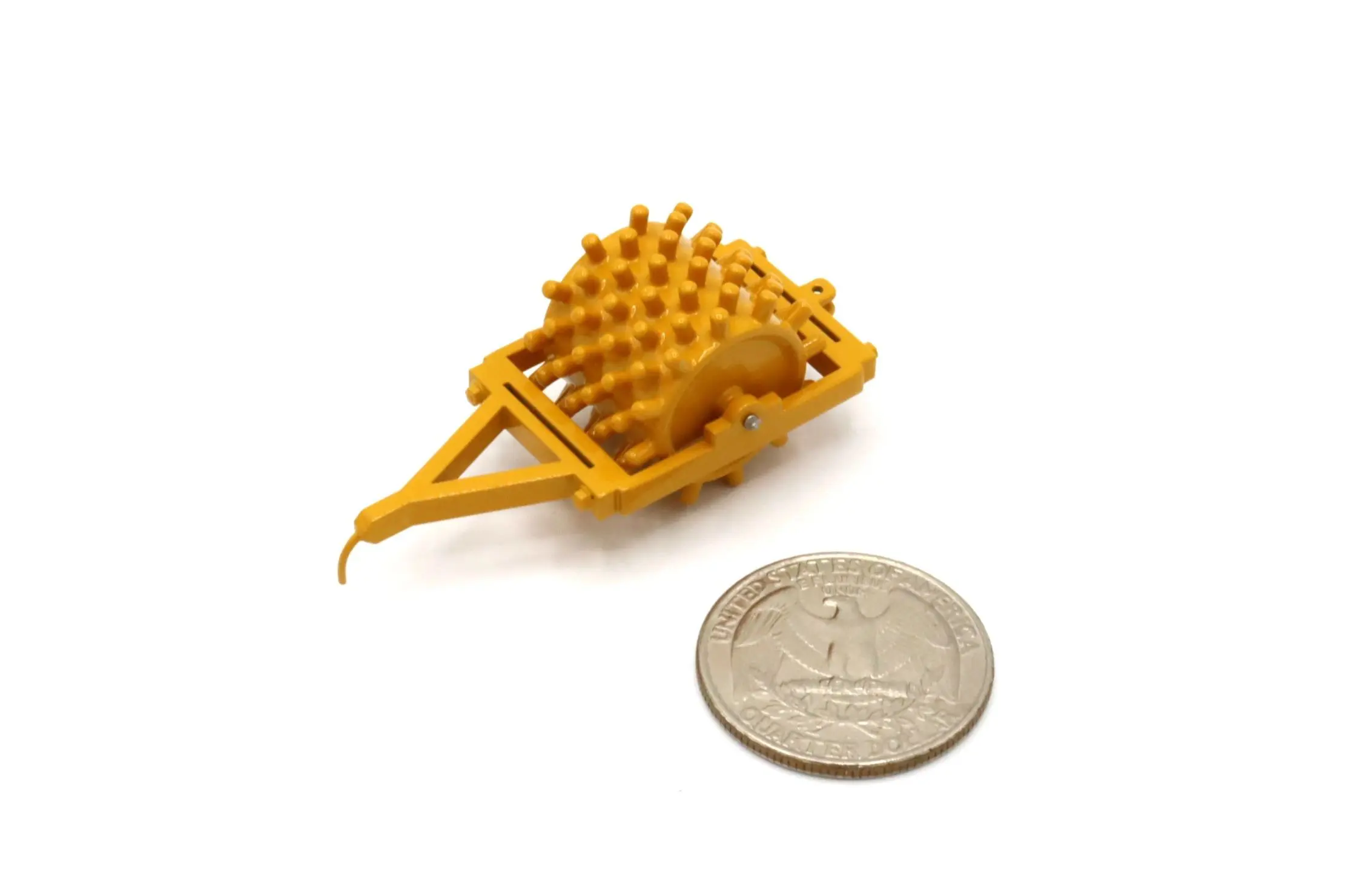A small yellow mechanical device next to a coin for scale.