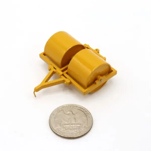 A tiny yellow wheelbarrow model next to a coin for scale.