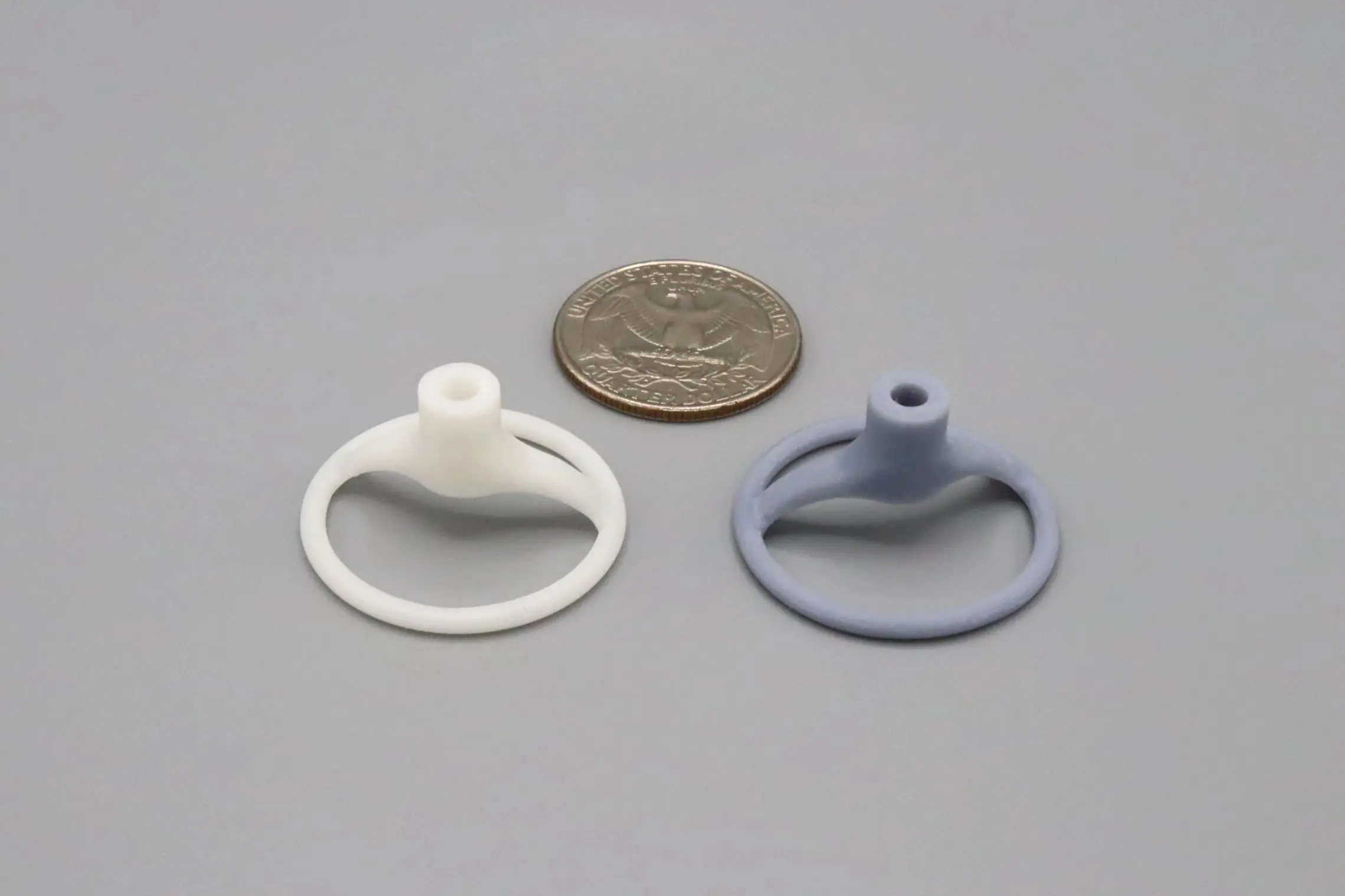 Two small silicone rings next to a coin for size reference.
