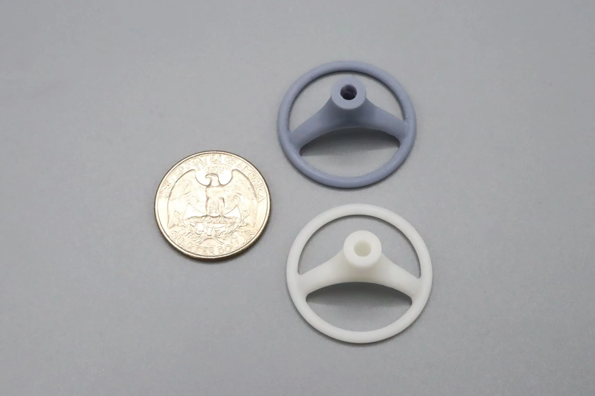 Two small plastic circular parts next to a quarter for scale.