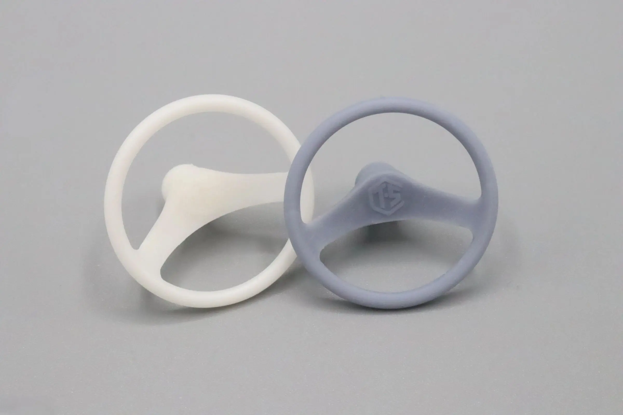 Two three-spoke steering wheels, one white and one light gray.
