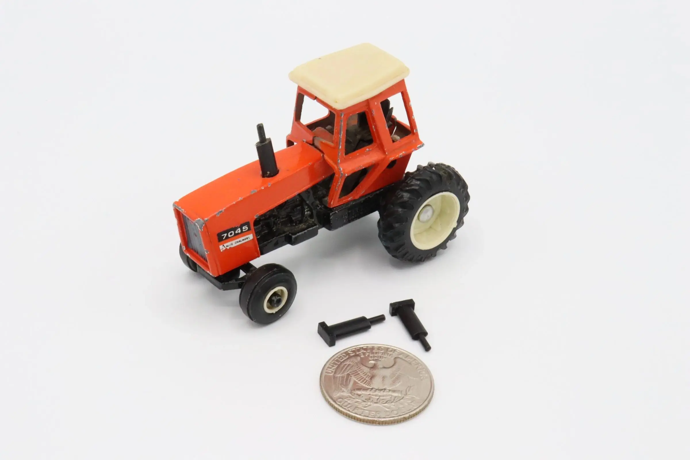 A small, detailed toy tractor with a coin for scale.