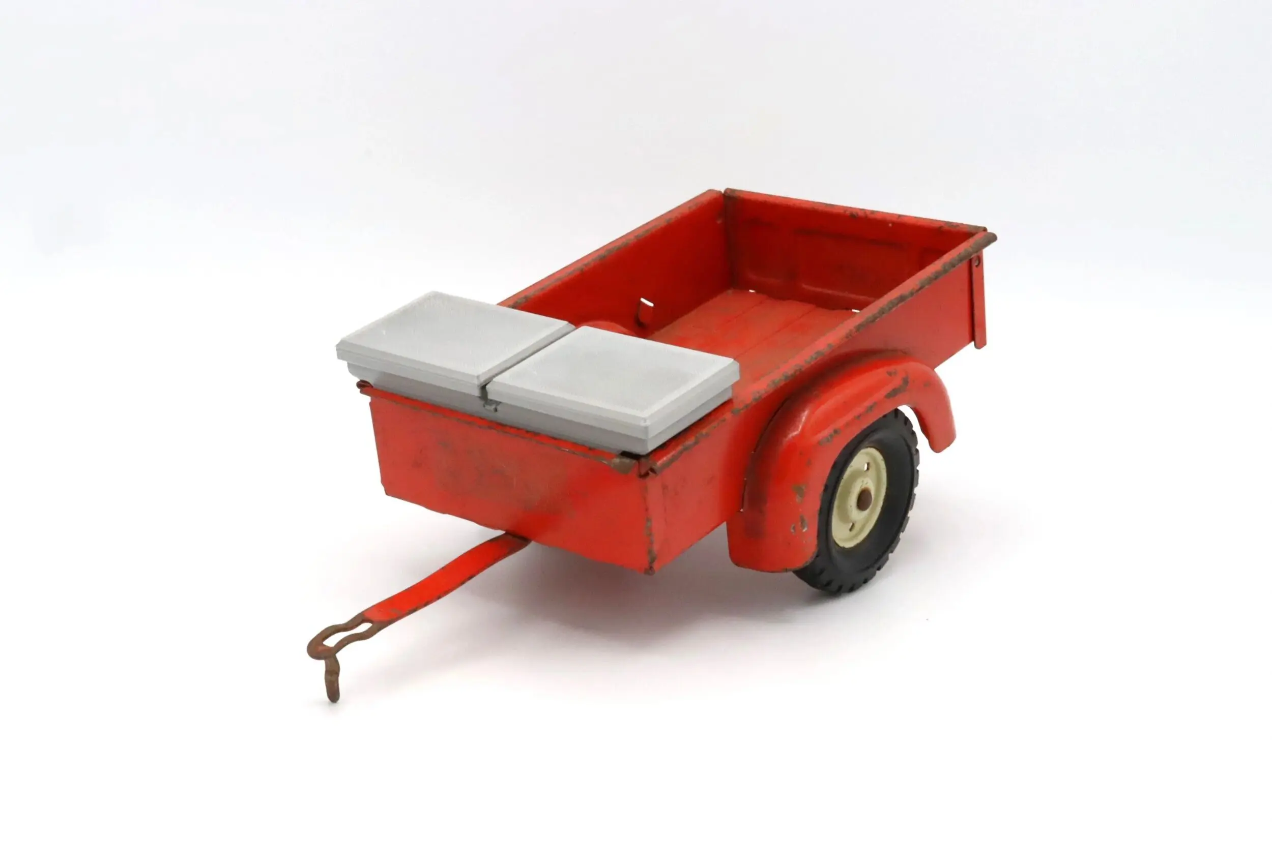 A small red utility trailer with a gray cover and a single wheel on each side.