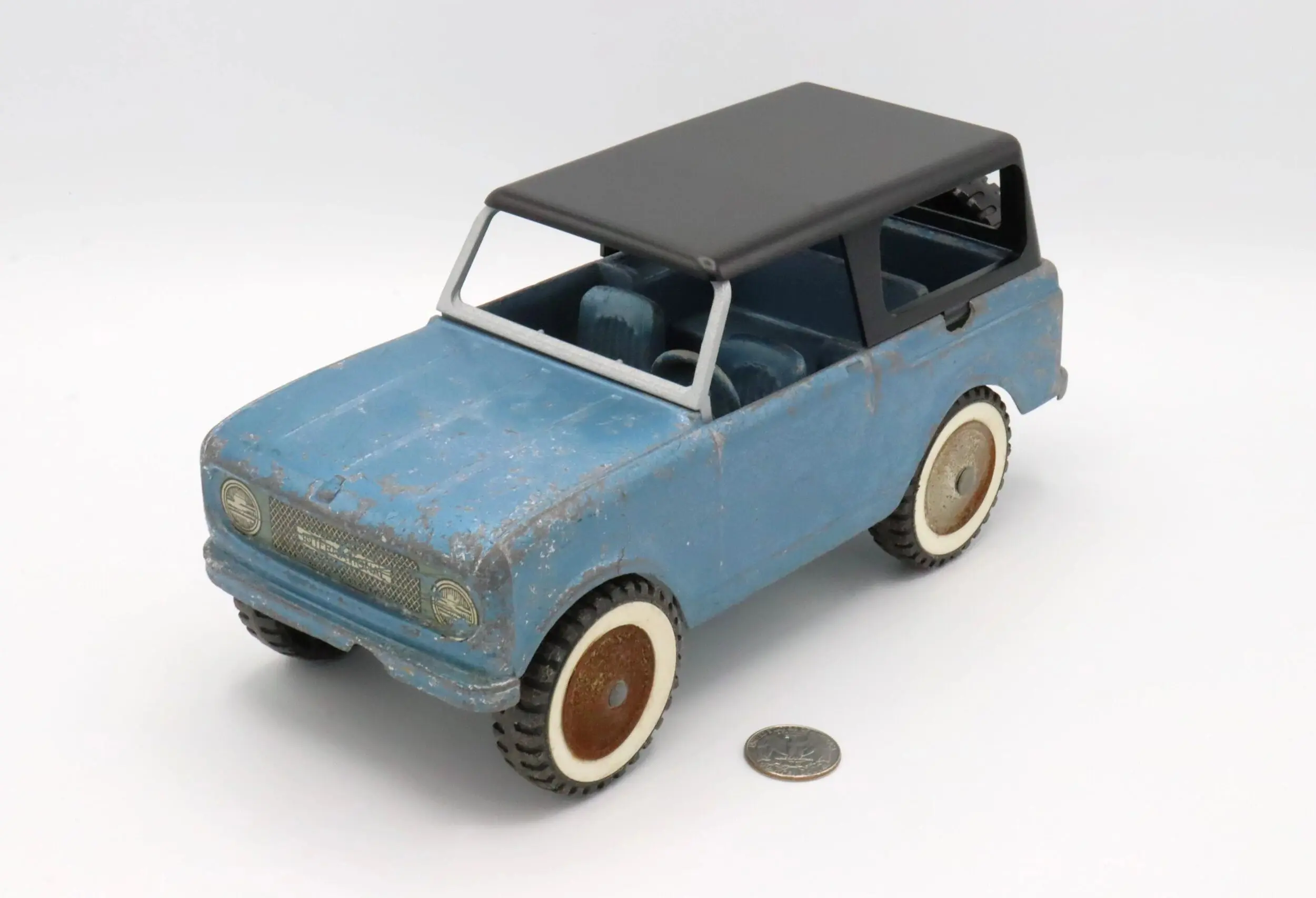 Vintage blue toy car with white wheels beside a coin for scale.