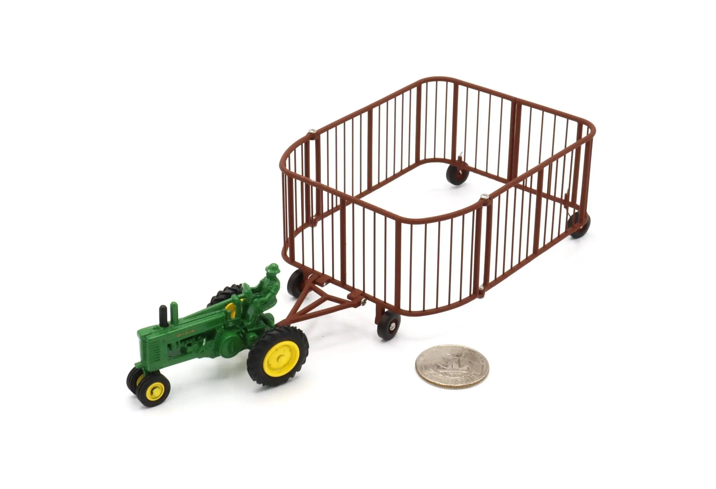 Miniature green tractor with brown cage trailer and coin for scale.