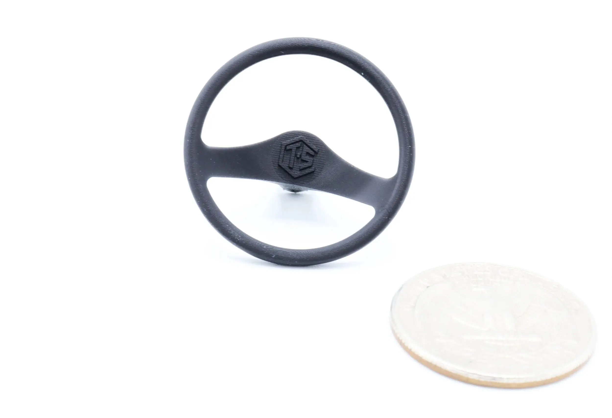 Black steering wheel with a white coin beside it for size reference.