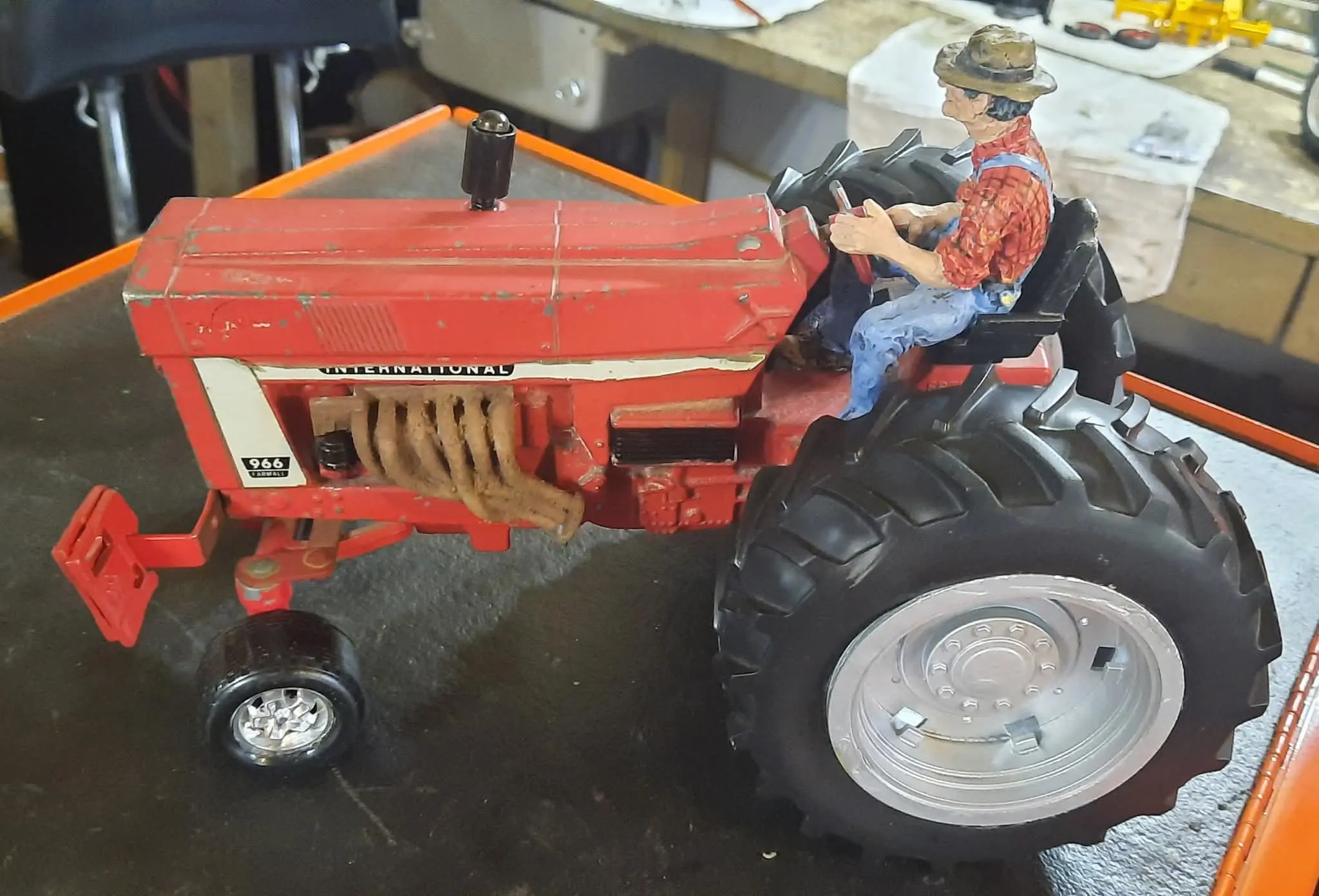 A detailed toy tractor with a figurine driver in an indoor setting.