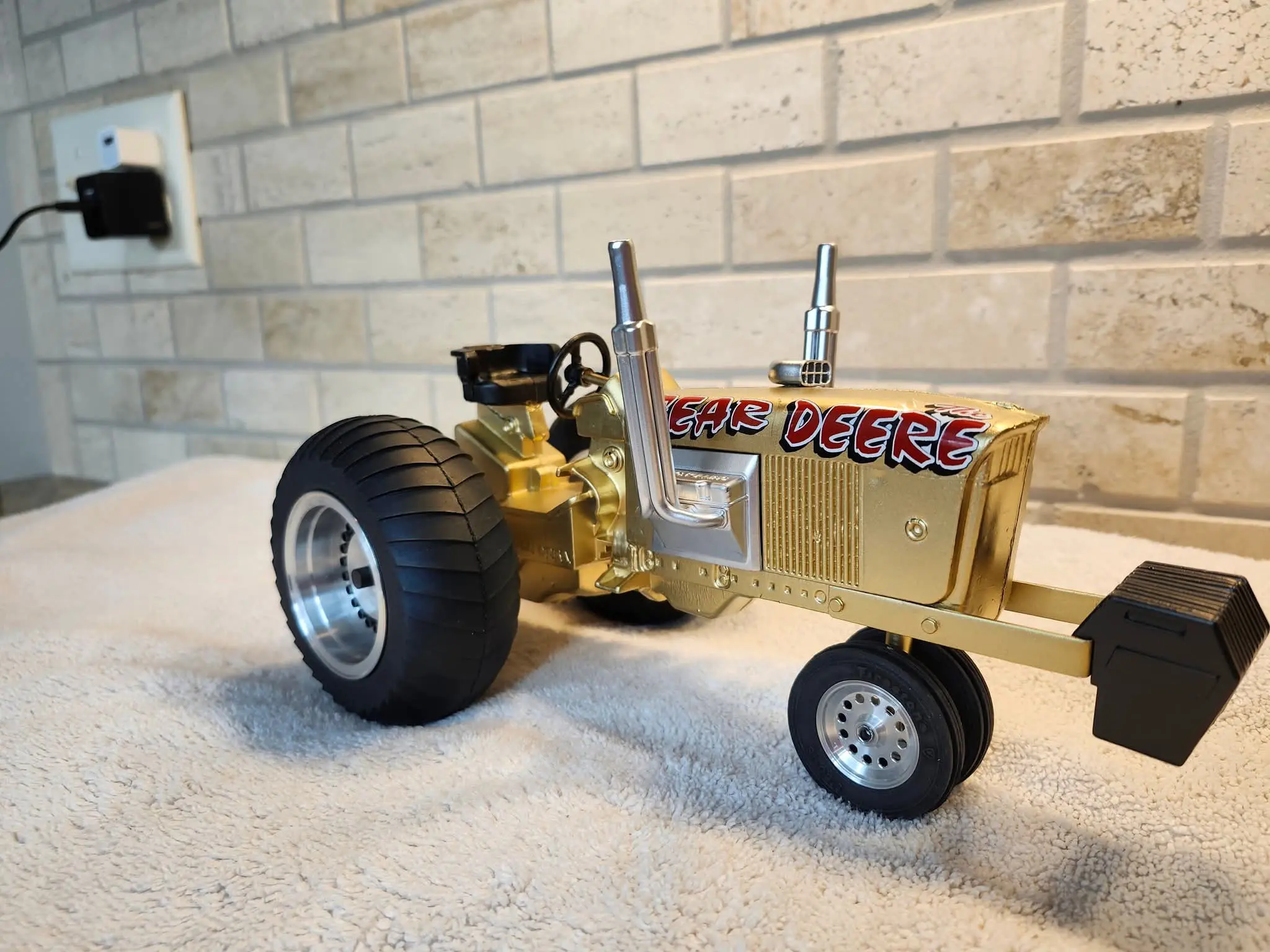 A miniature vintage tractor model with large rear wheels and a shiny metallic body.