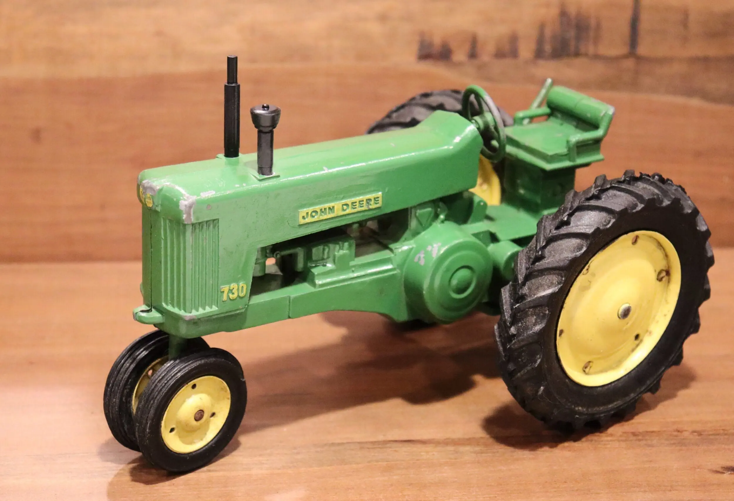 Close-up of a vintage green tractor model with detailed wheels and engine.