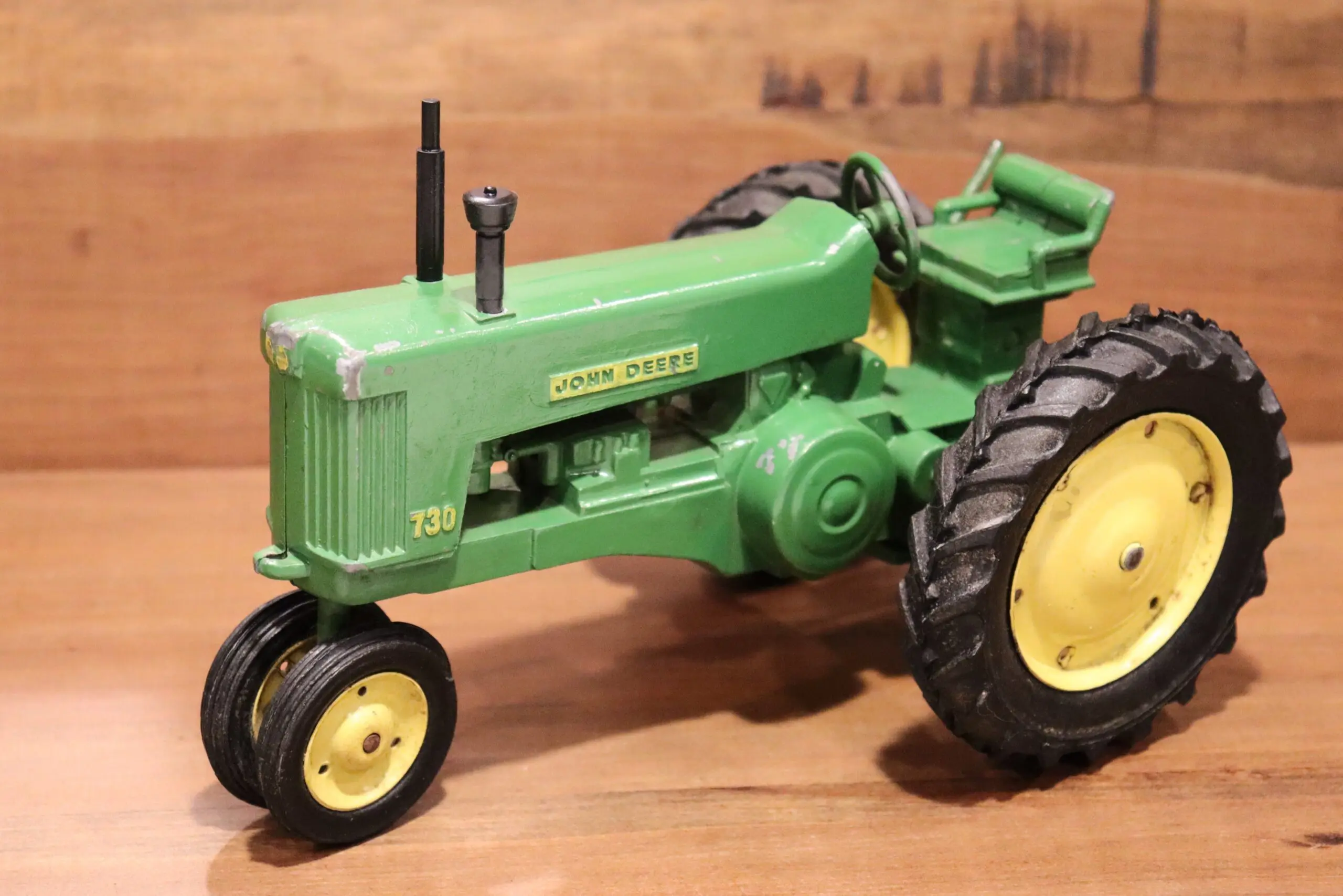 Close-up of a vintage green tractor model with detailed wheels and engine.