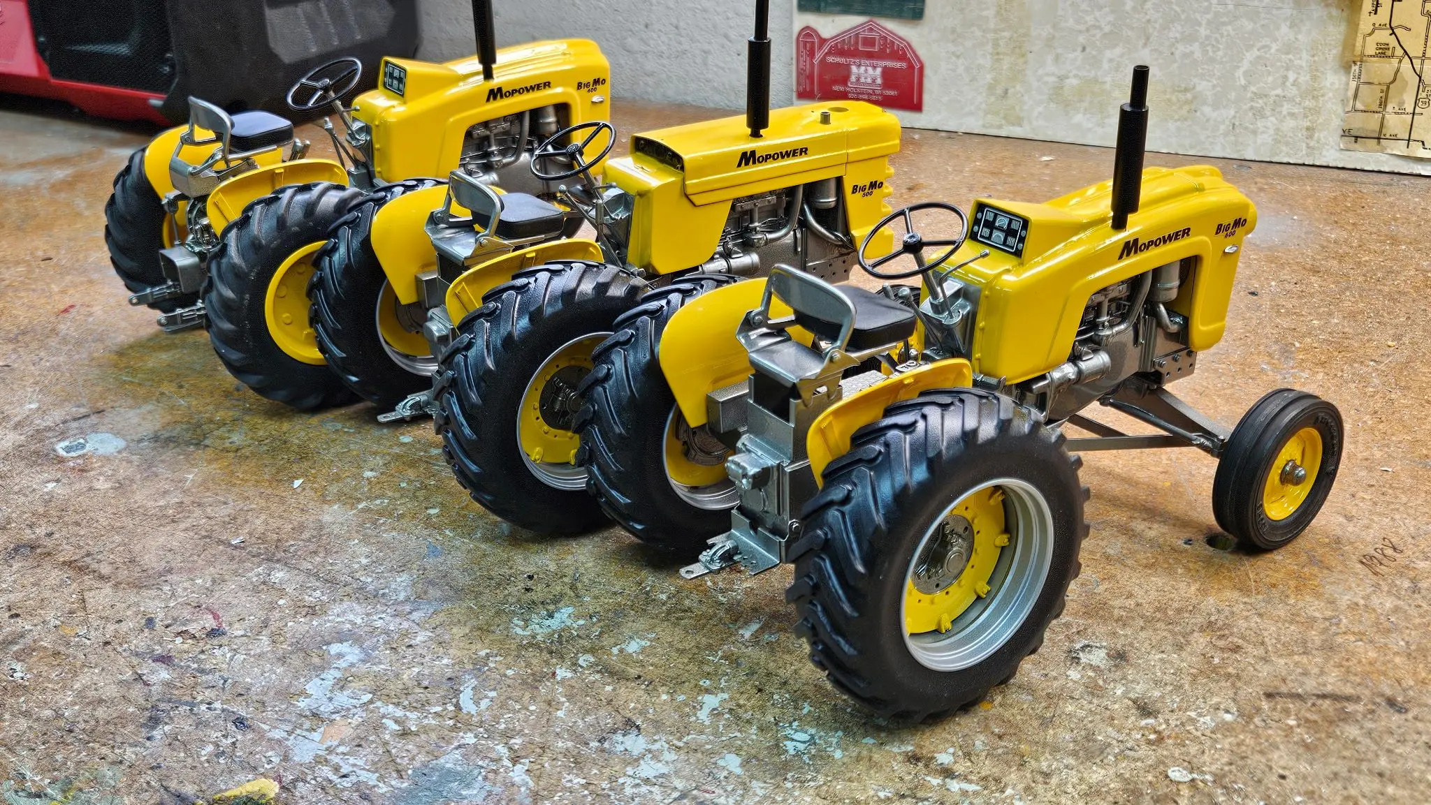 Three detailed yellow model tractors displayed in a row.