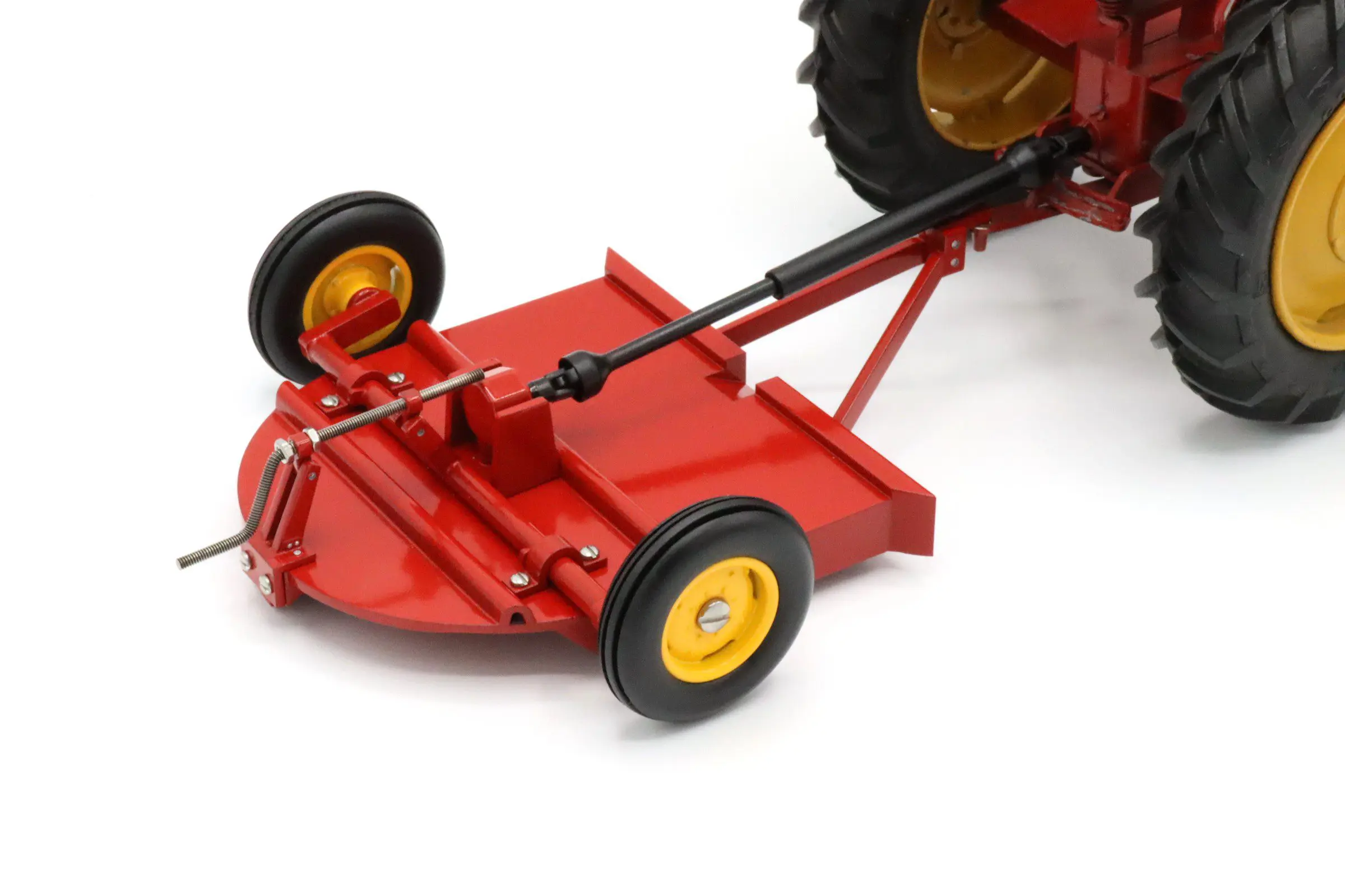 Close-up of a red lawn mower attachment with yellow wheels.