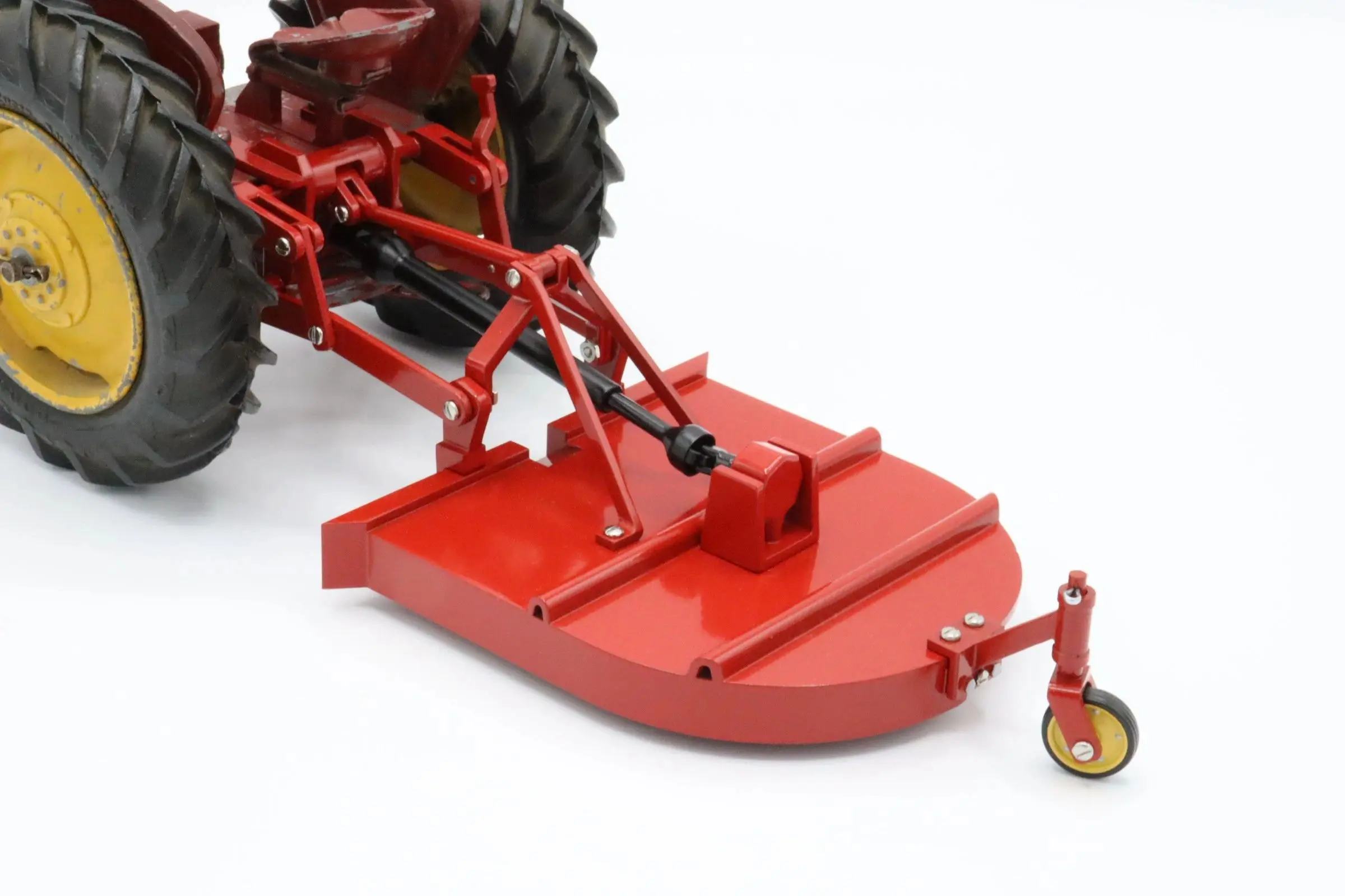 Red rotary mower attached to a tractor's rear.