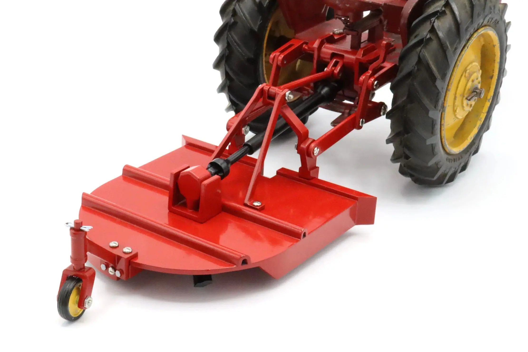 Red rotary mower attachment connected to tractor.