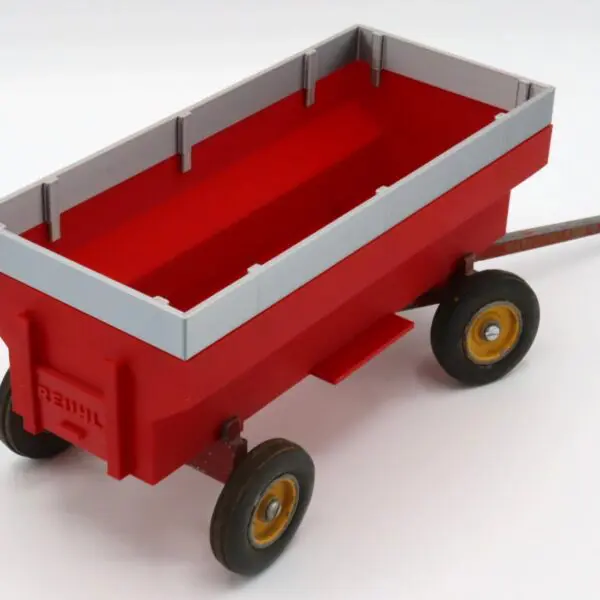 Red toy wagon with yellow wheels and gray railing.