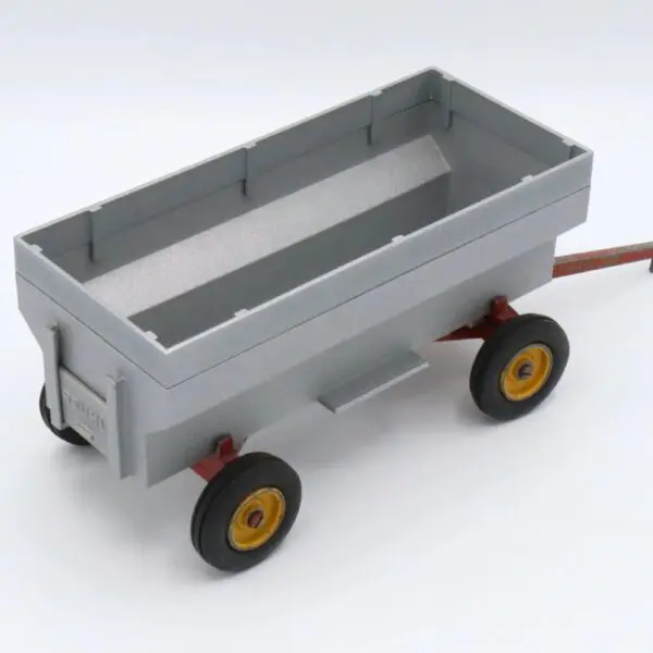 A small gray toy wagon with red handle and black wheels.
