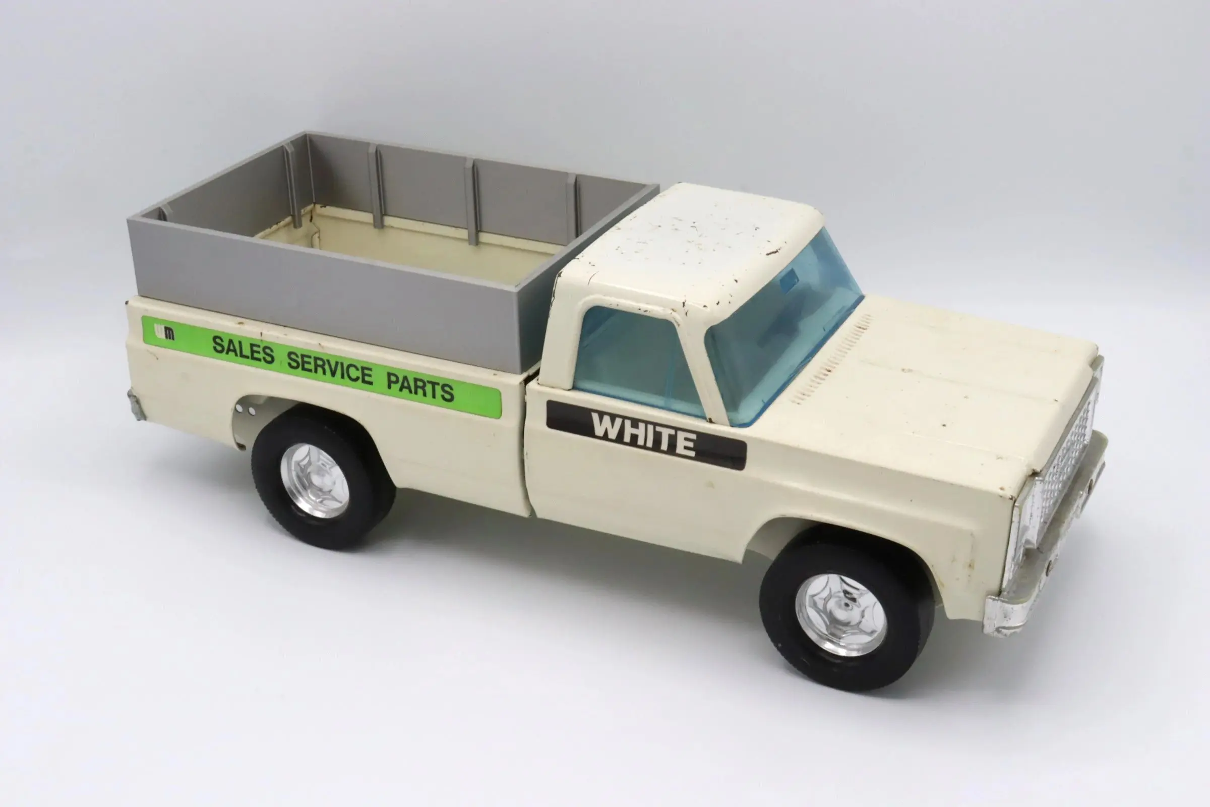 Vintage white toy pickup truck with green details and flatbed.