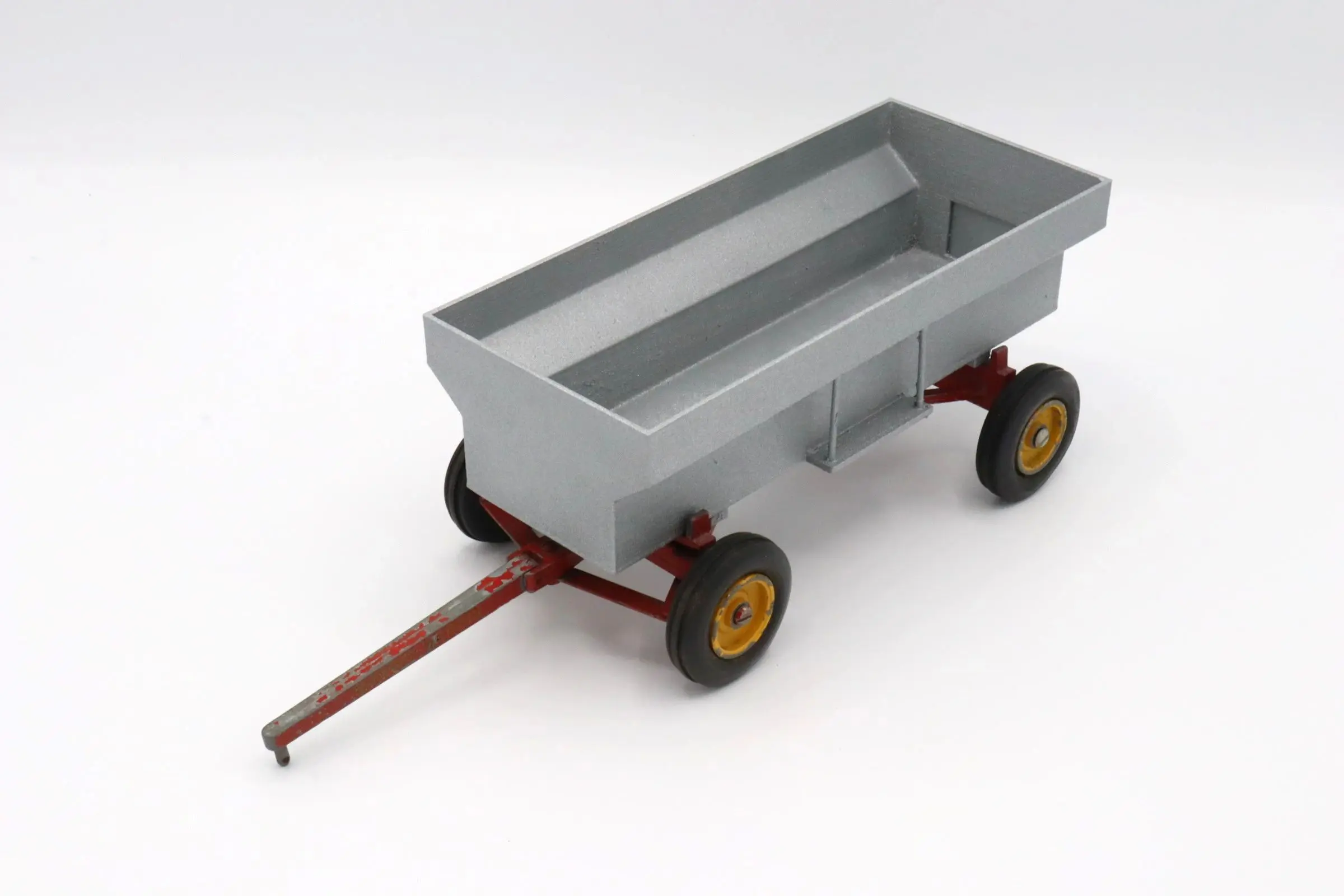 A gray toy wagon with four wheels and a red handle.