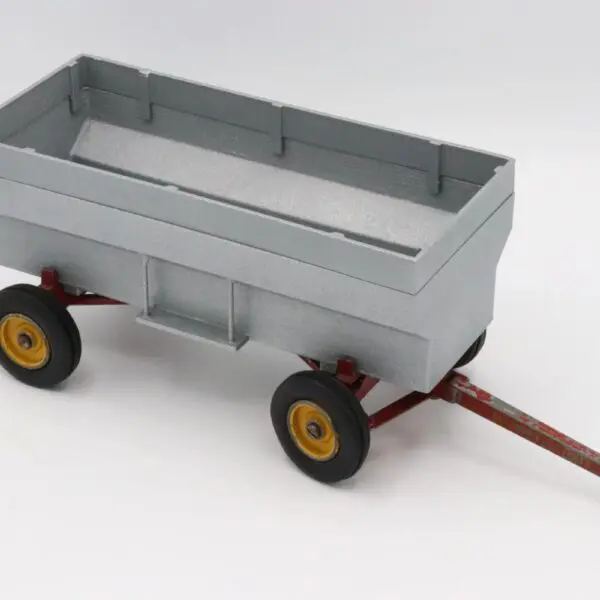 A small gray toy wagon with yellow wheels and a red handle.