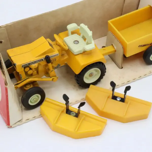 Vintage yellow toy tractor with detachable parts, including a trailer and front loader.