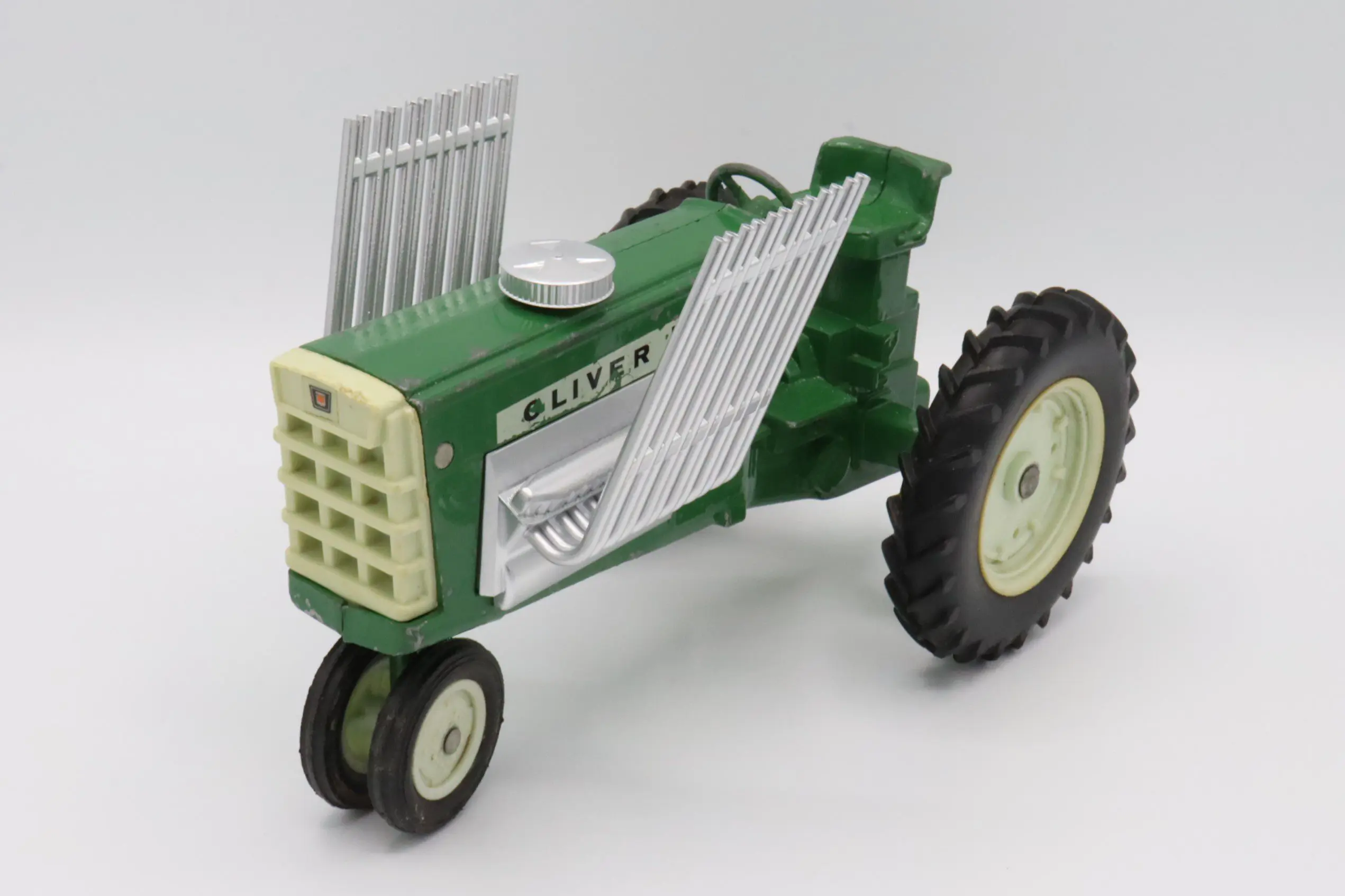 A vintage green and white toy tractor with large rear wheels and smaller front wheels.